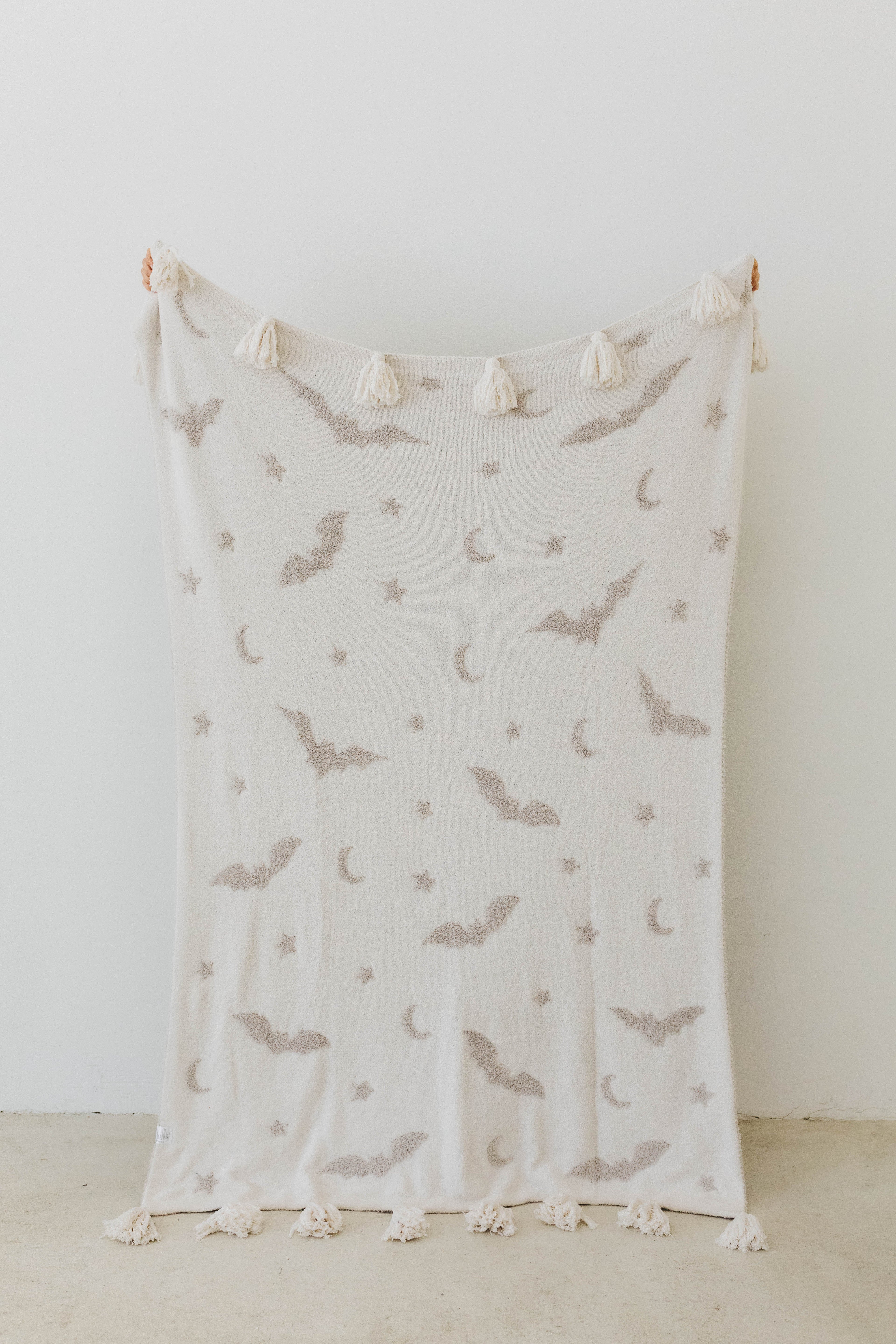one side of bat tassel blanket - white with grey bats, moons, and stars