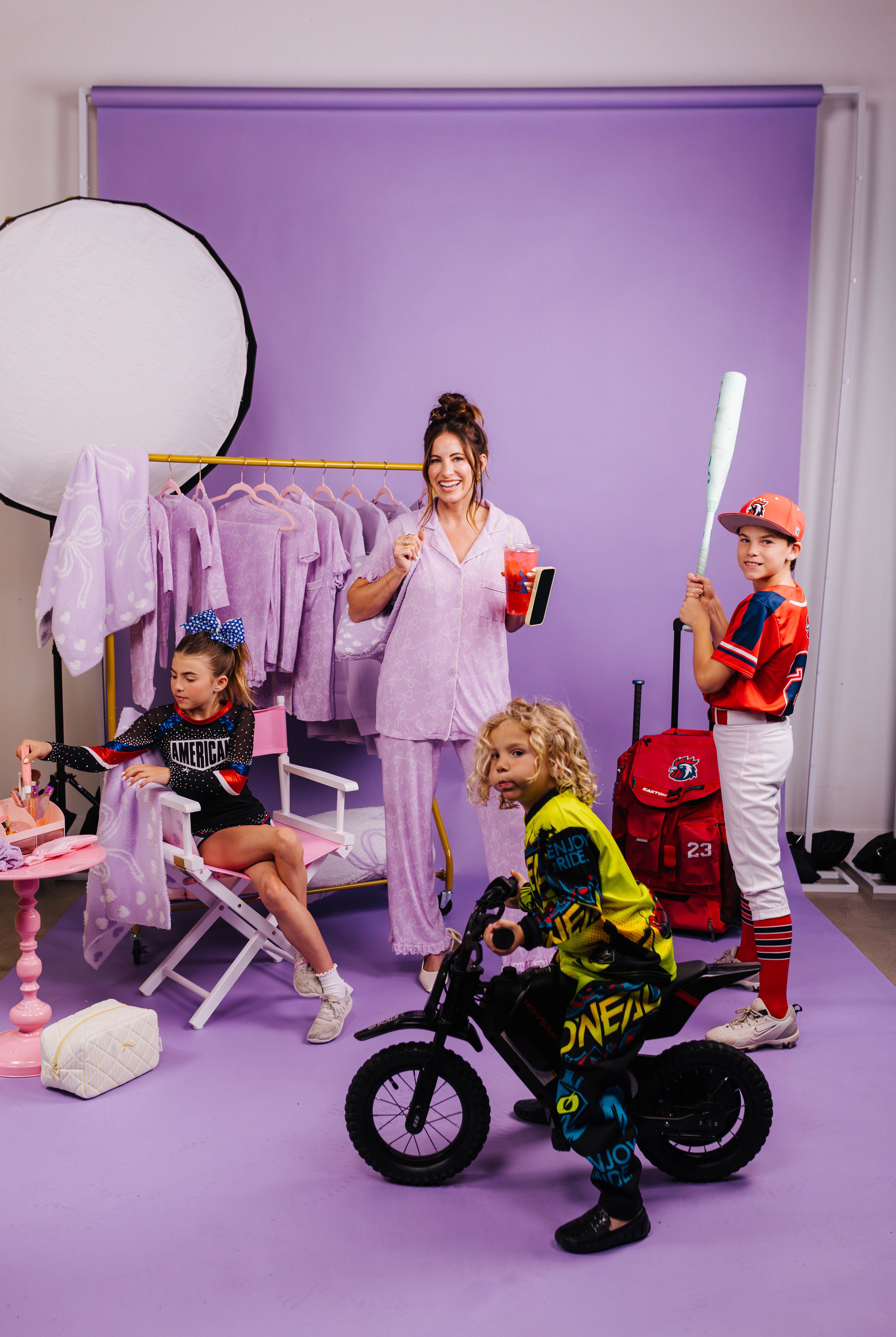 Children in colorful outfits with a woman in a studio setting