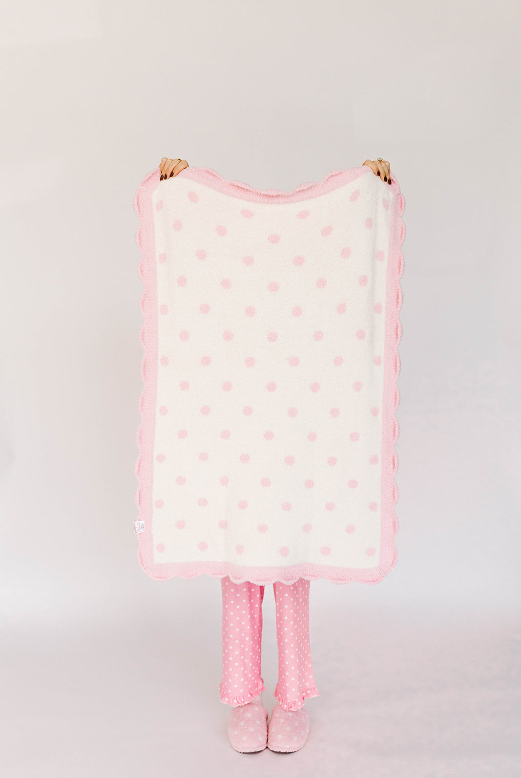 Pink polka dot blanket with matching tights on a white background