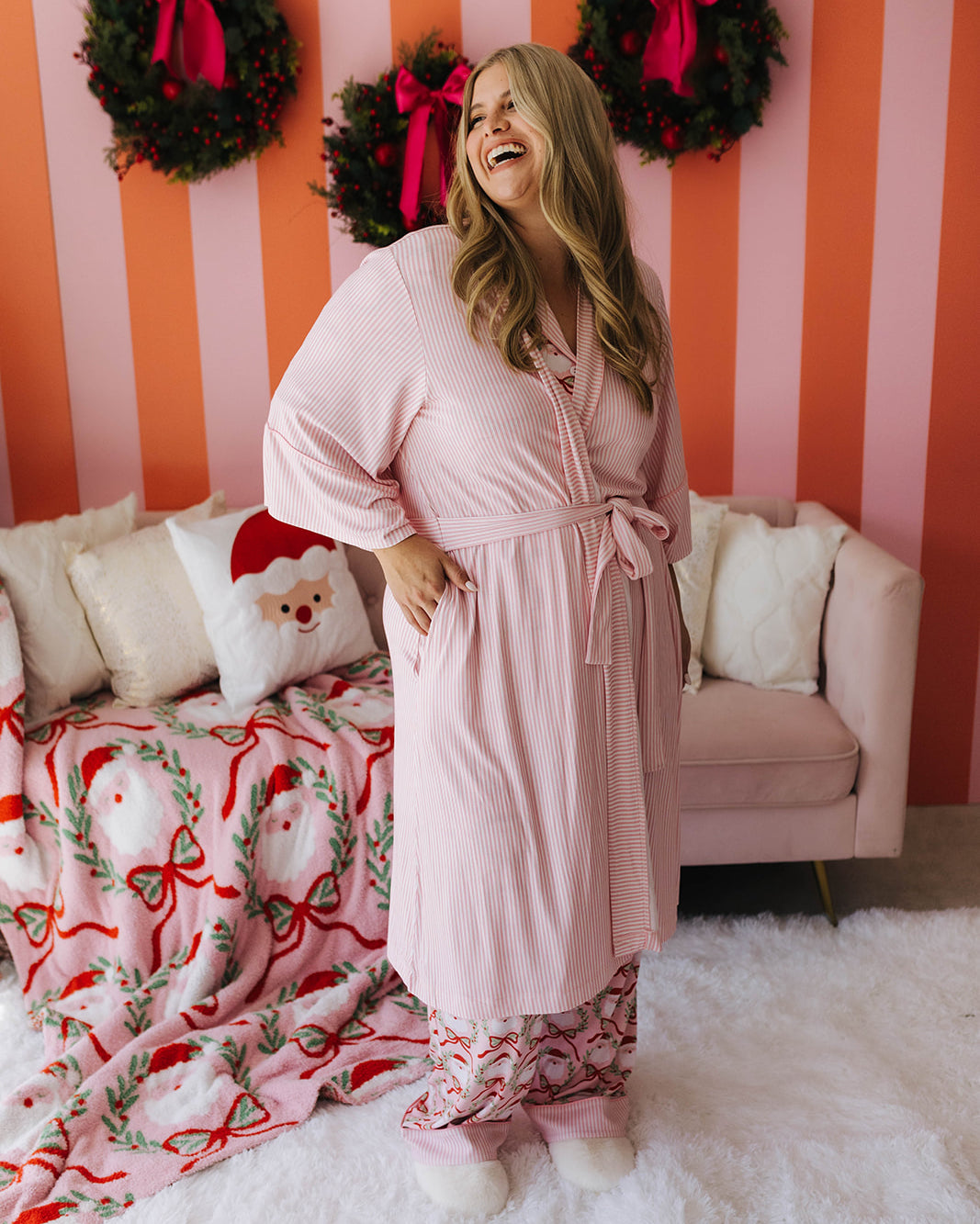 Woman in a pink robe standing in a room with Christmas decorations.
