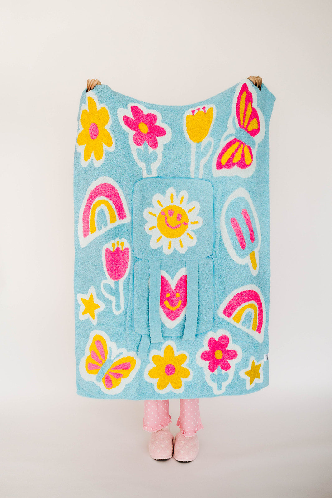 Children's blanket with colorful floral, rainbow, and sun patterns on a white background.
