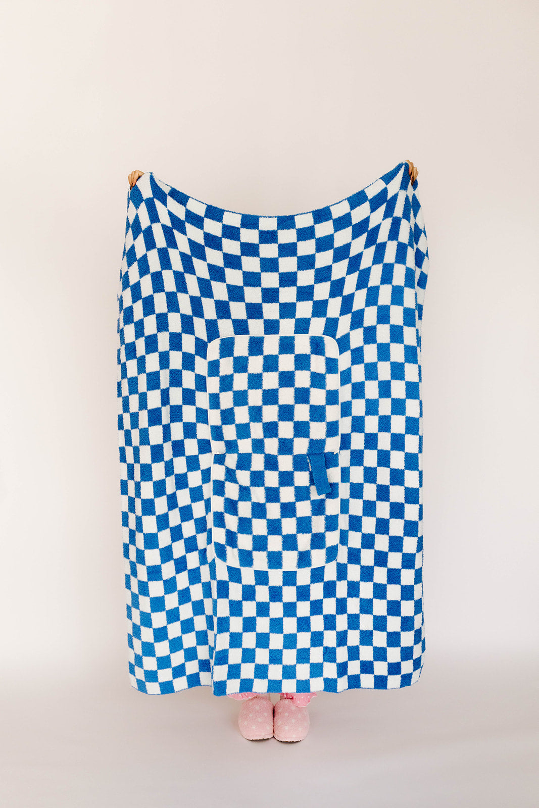 Blue and white checkered blanket draped over a person on a plain background