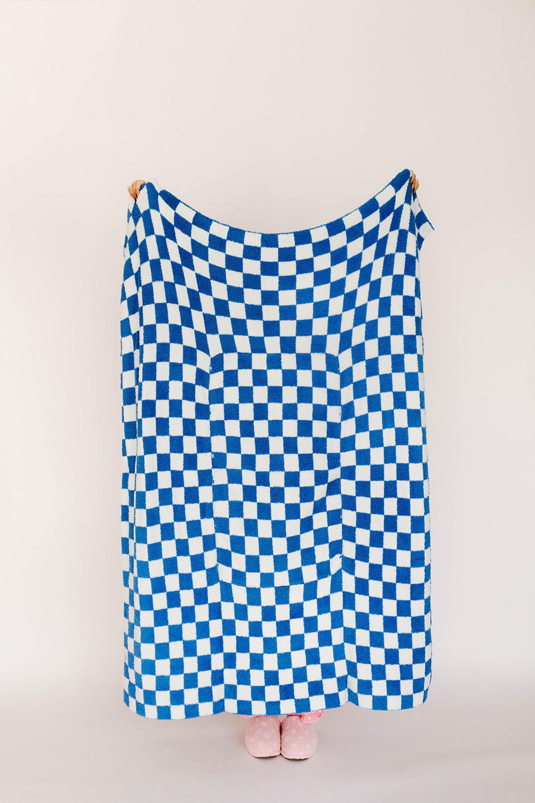 Blue and white checkered blanket draped over a person on a plain background