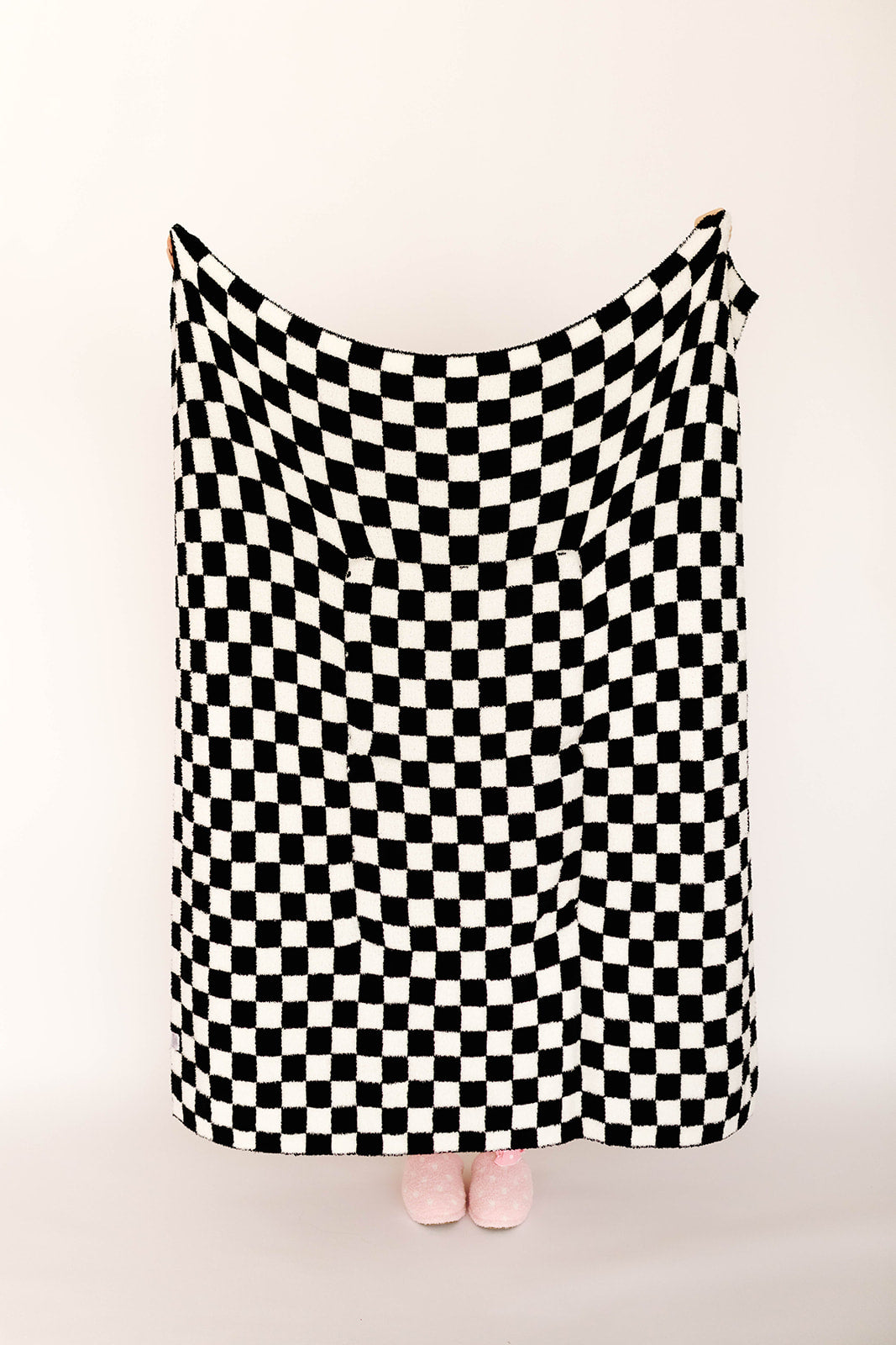 Black and white checkered blanket draped over a person on a beige background
