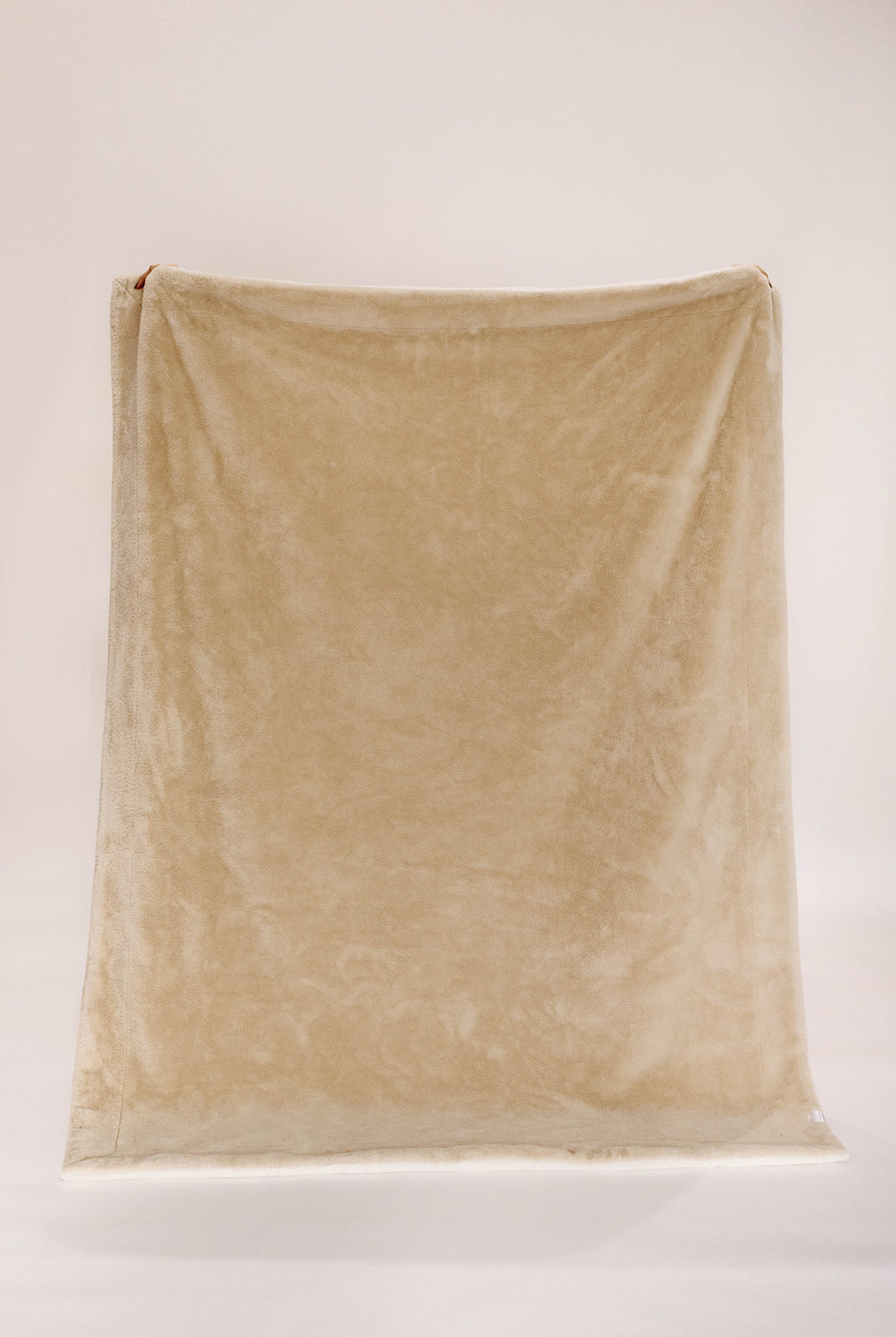 Beige blanket draped over a white surface