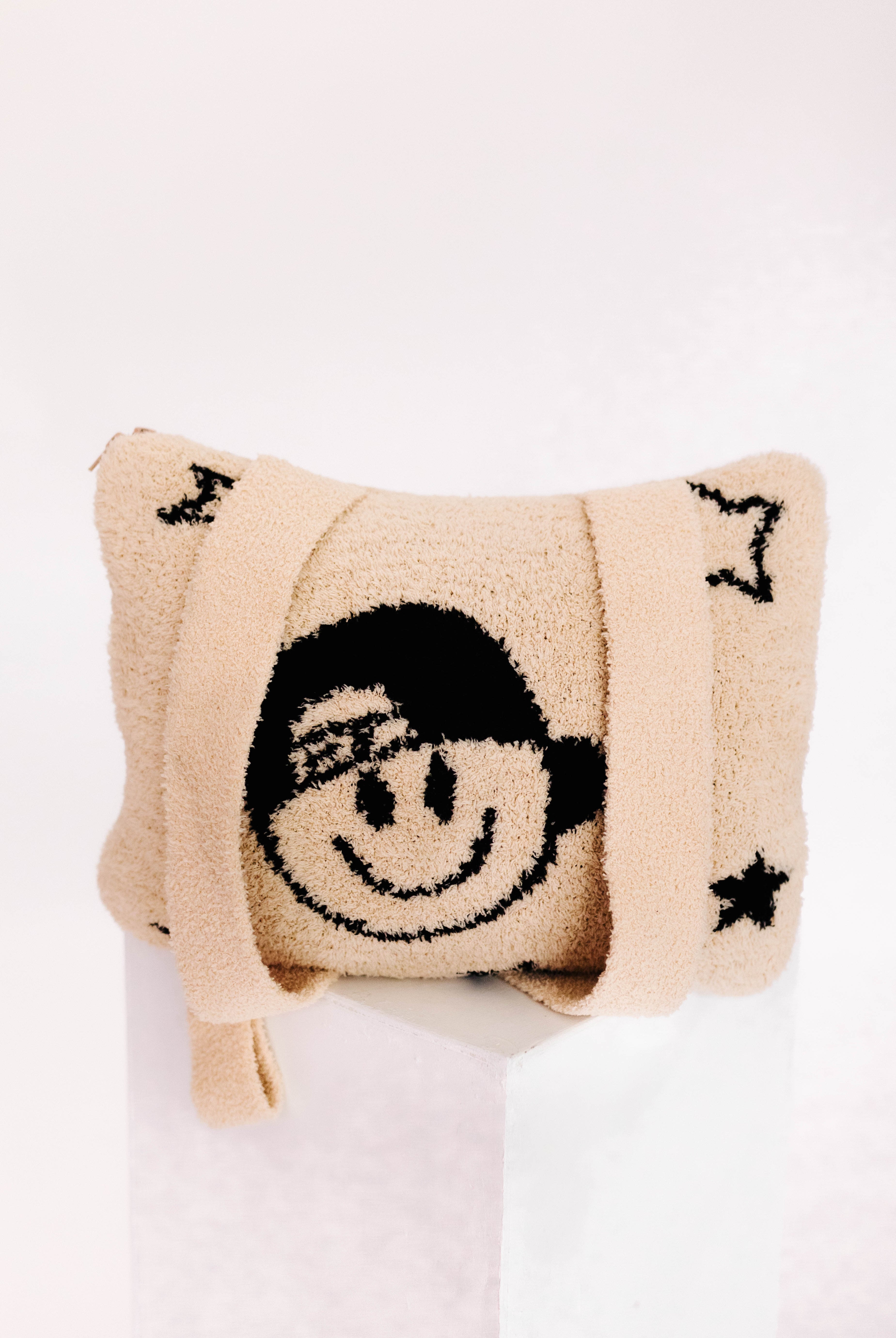 Beige quillow with a smiley face design on a white background