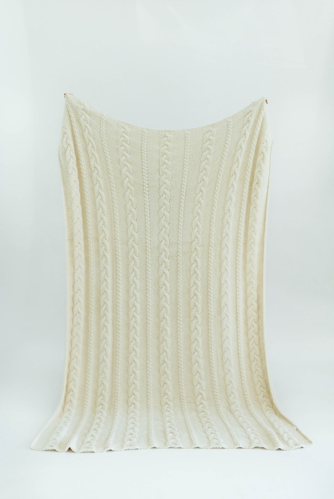 Cream-colored knitted blanket on a white background