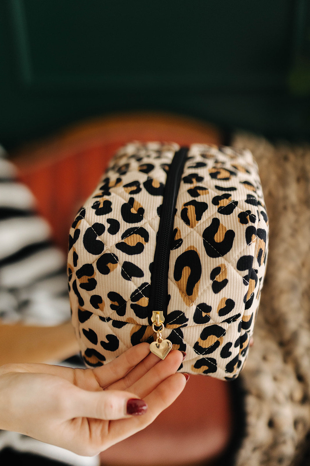 Leopard print makeup bag held by a hand with a blurred background