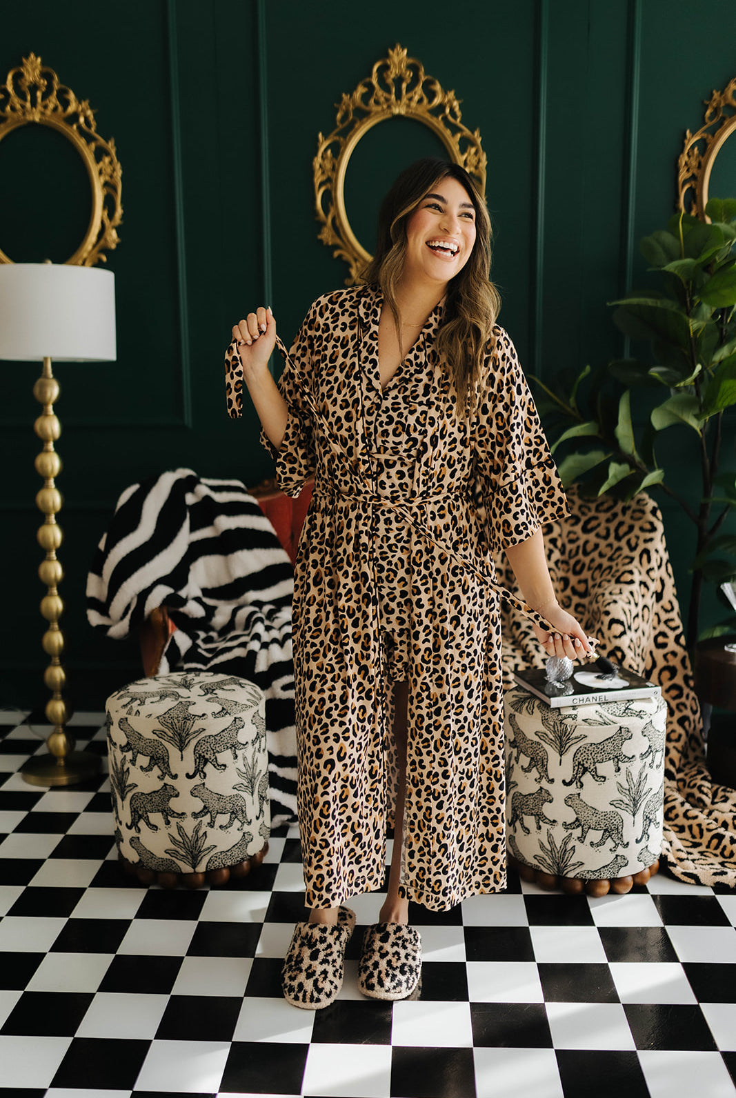 Woman in leopard print robe standing in a stylish room with decorative mirrors and furniture.