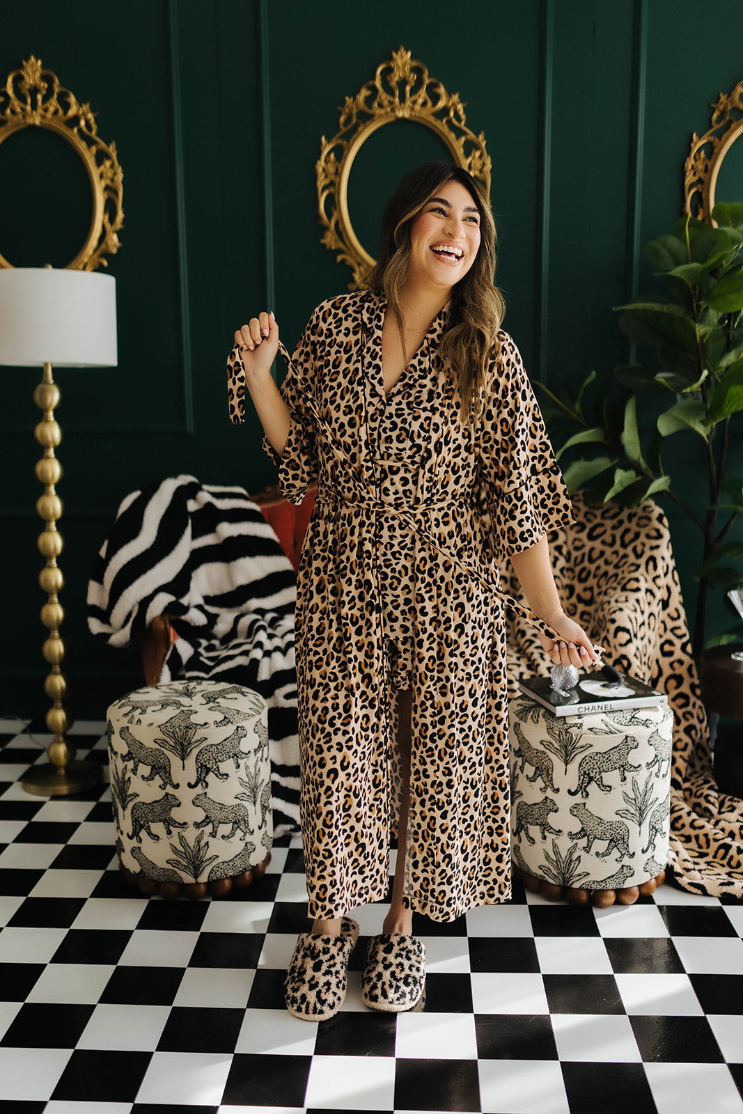 Woman in leopard print robe standing in a stylish room with decorative mirrors and furniture.