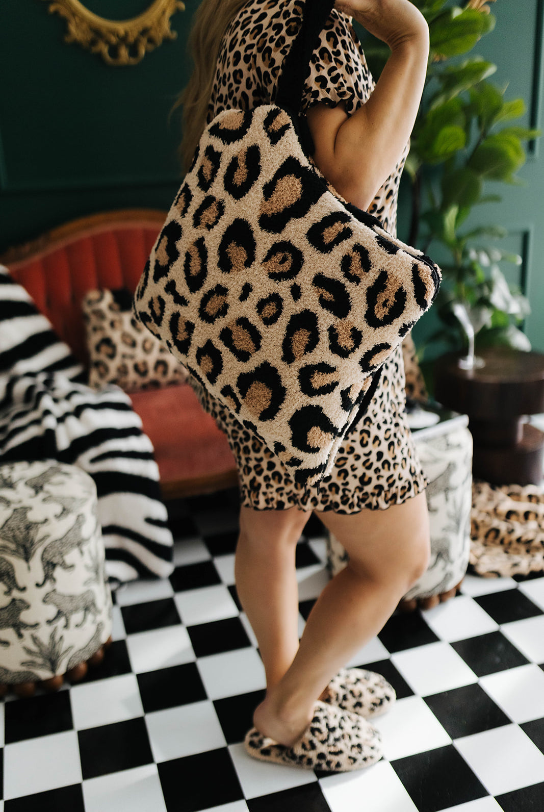 Person wearing a leopard print pajama set and slippers in a room with checkered floor and decorative elements.