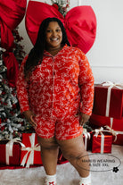 Person wearing a red pajama set with white bow patterns in a festive setting with Christmas decorations.