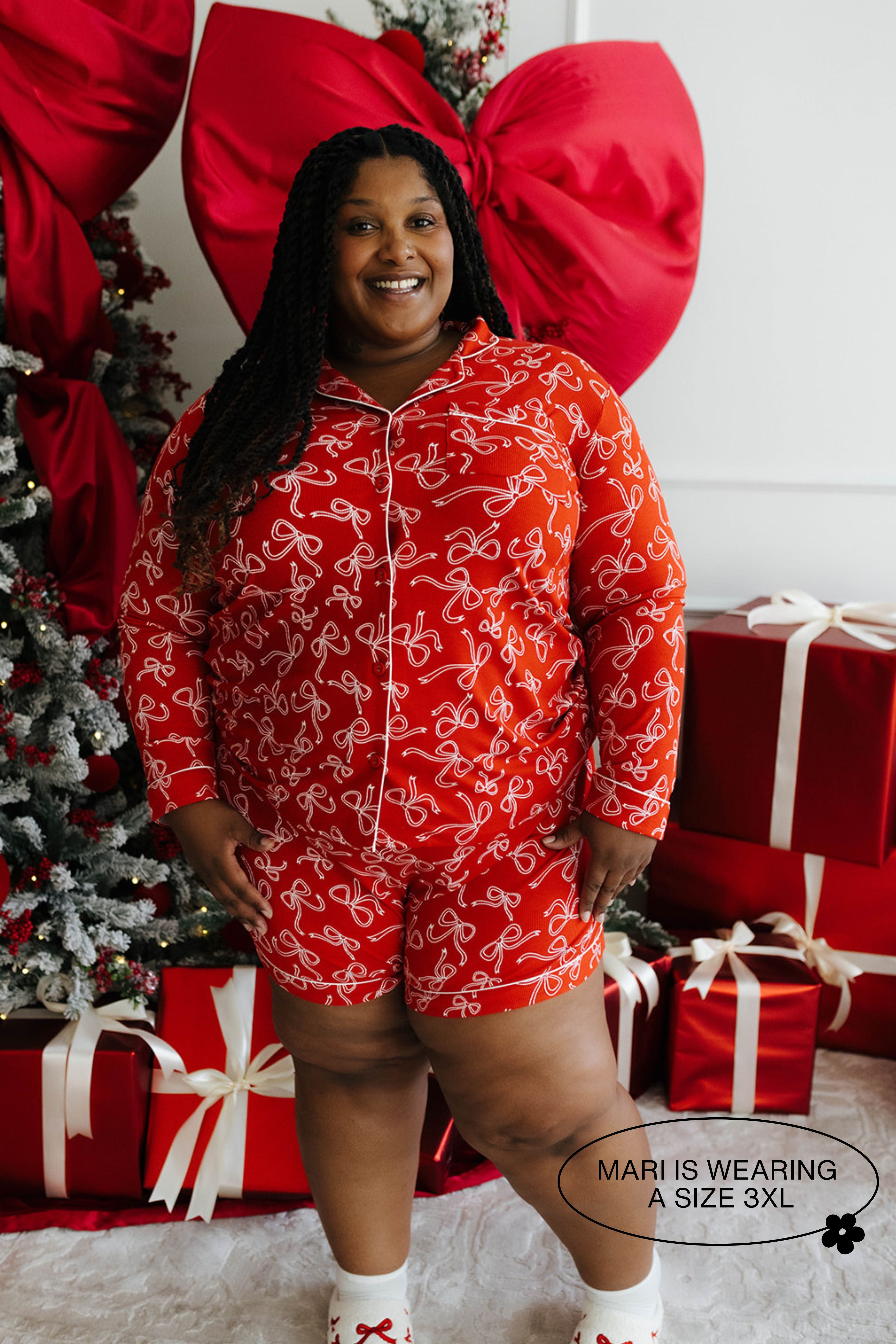 Person wearing a red pajama set with white bow patterns in a festive setting with Christmas decorations.