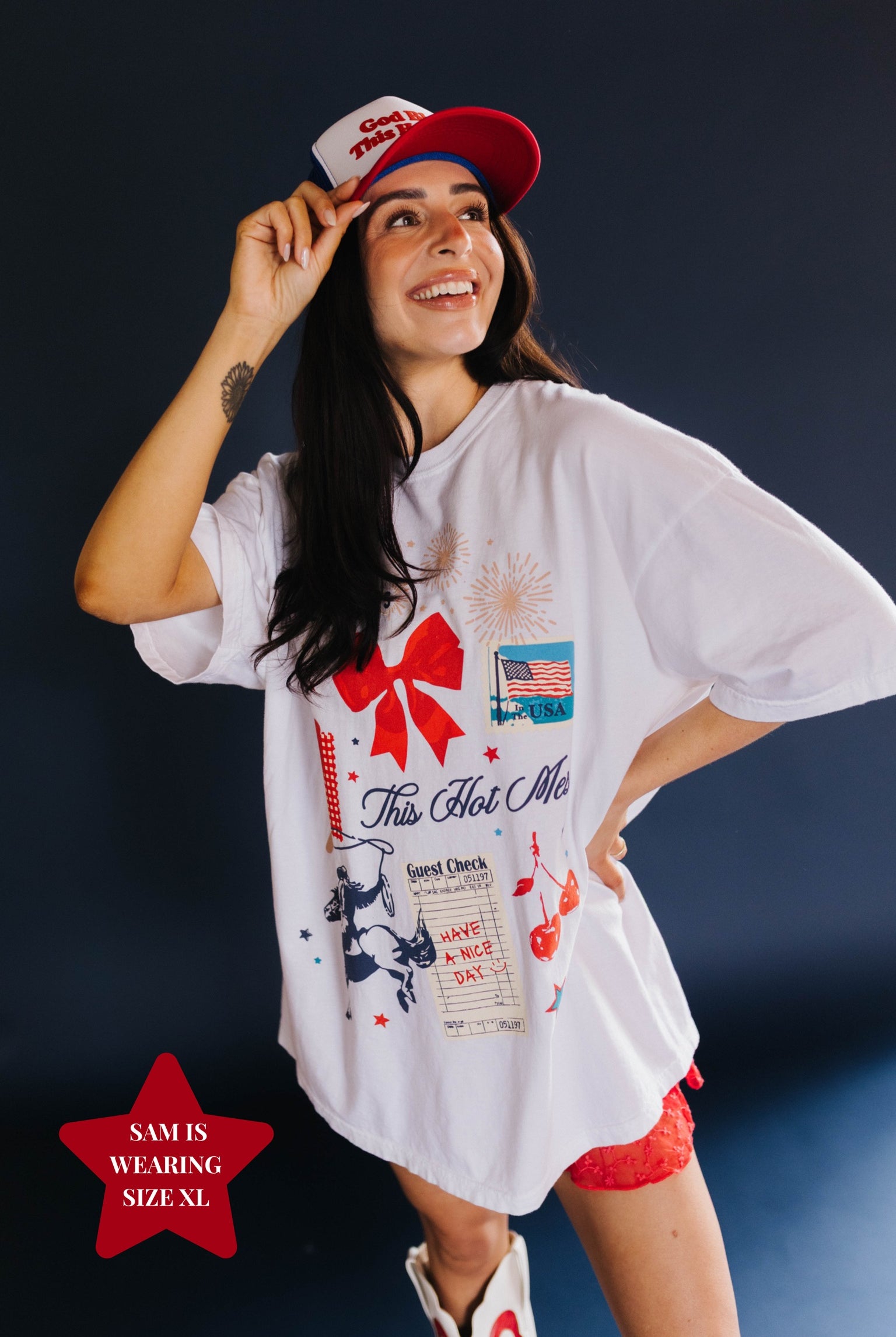 Woman wearing a white graphic t-shirt and red cap against a dark background