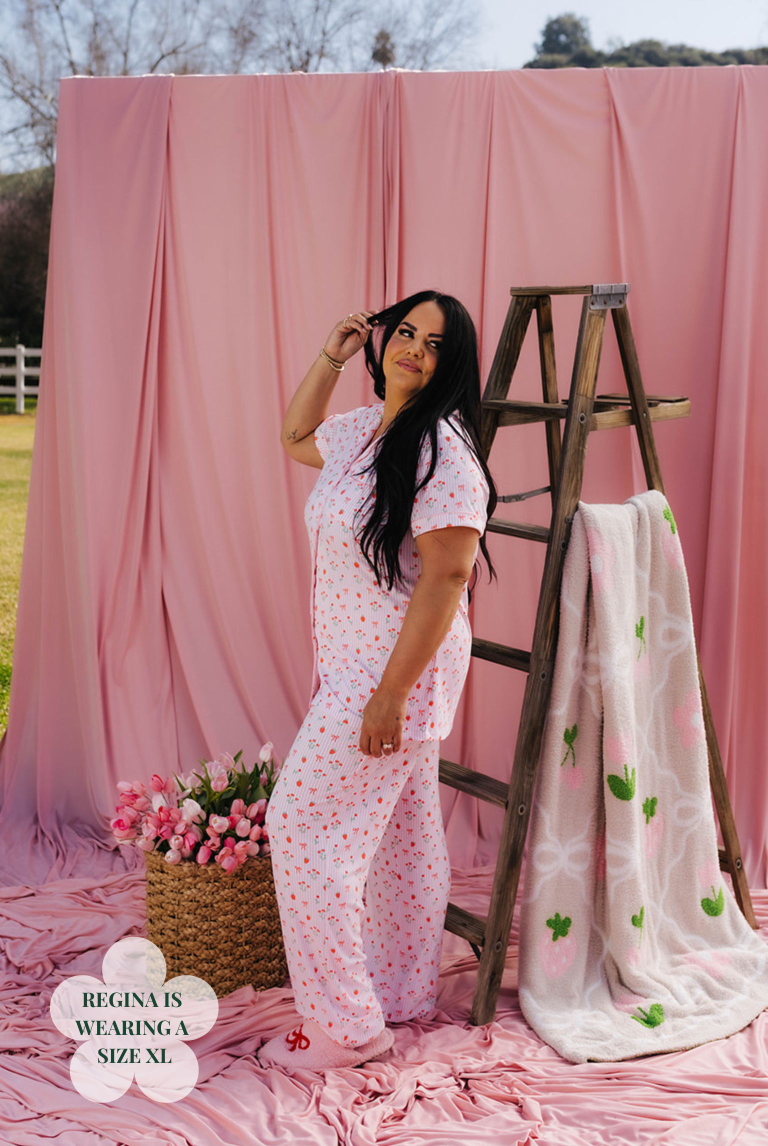 Woman in a pink outfit standing next to a wooden ladder with a pink backdrop