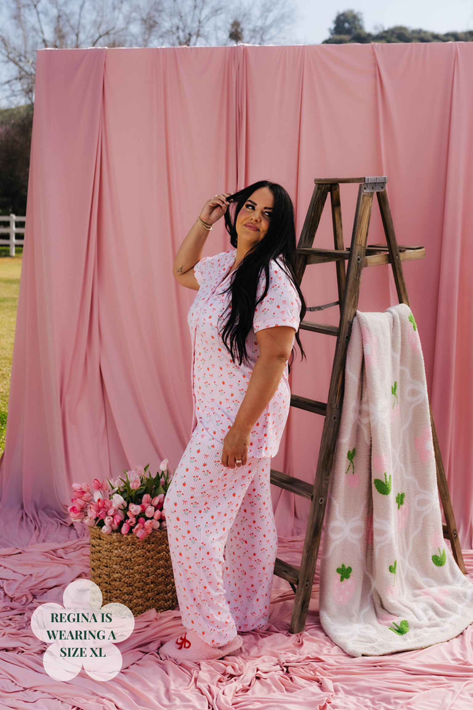 Woman in a pink outfit standing next to a wooden ladder with a pink backdrop