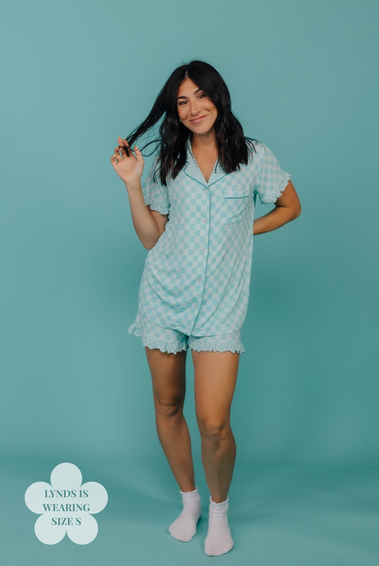 Woman wearing a teal check pajama set against a teal background