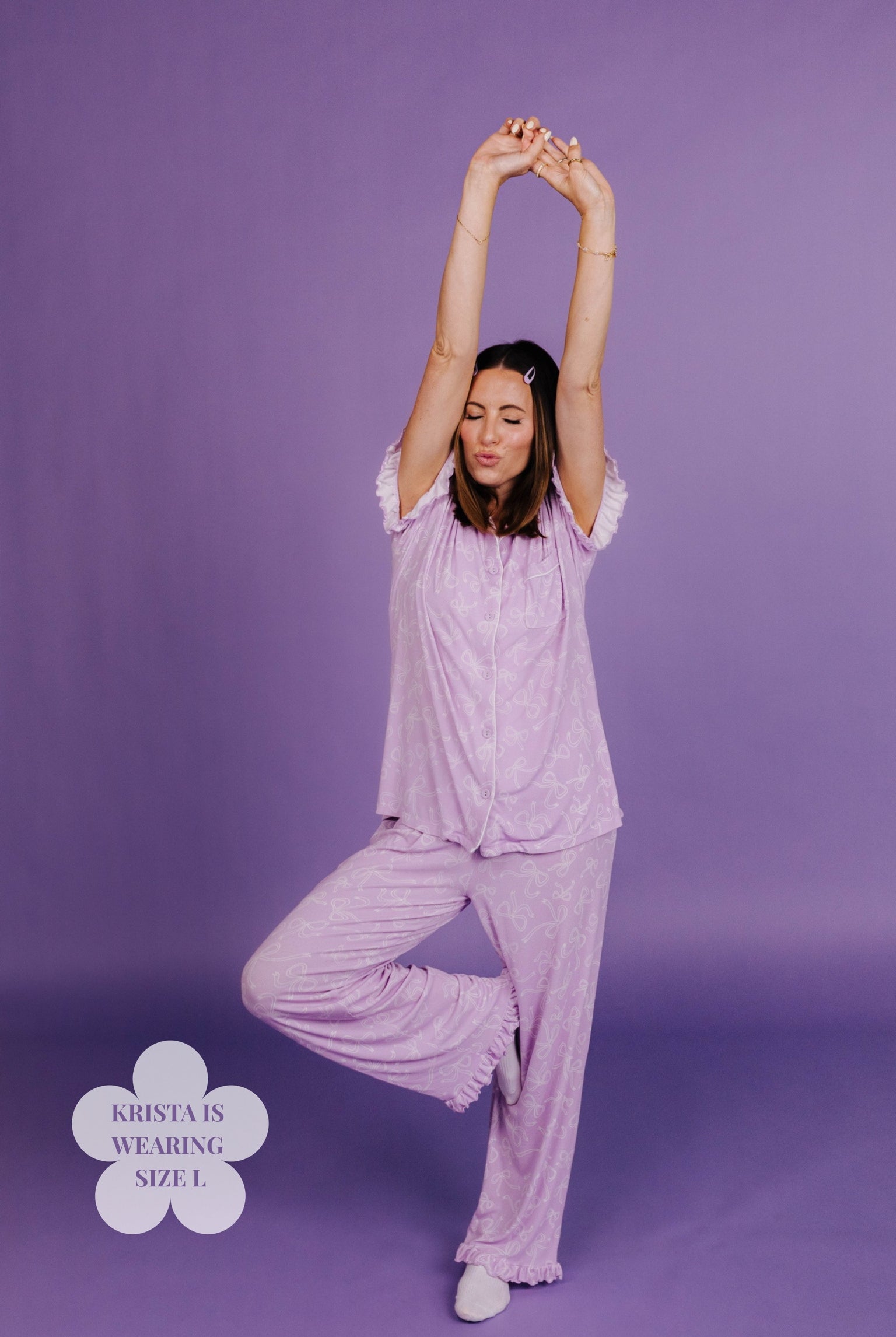 Woman in lavender pajama set stretching against a purple background