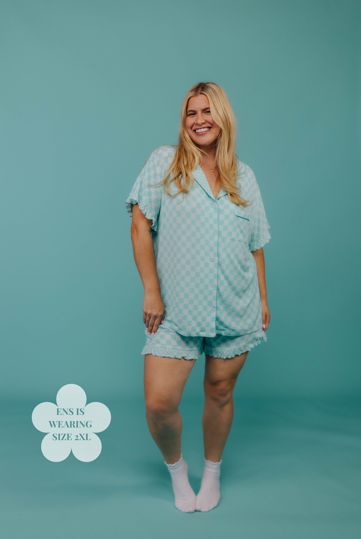 Woman wearing a teal patterned pj set on a teal background
