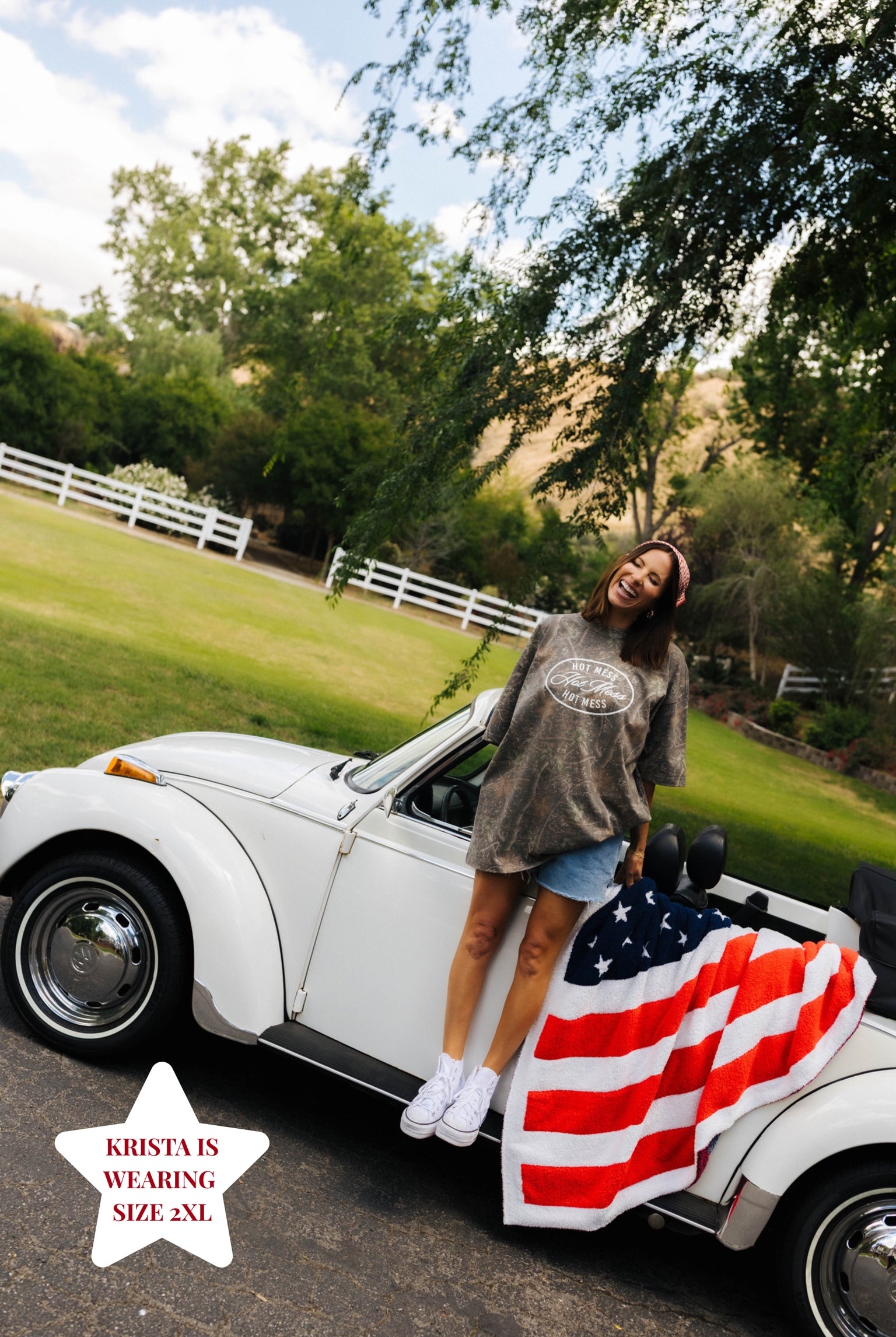 girl posing in front of white bug outside in camo tee