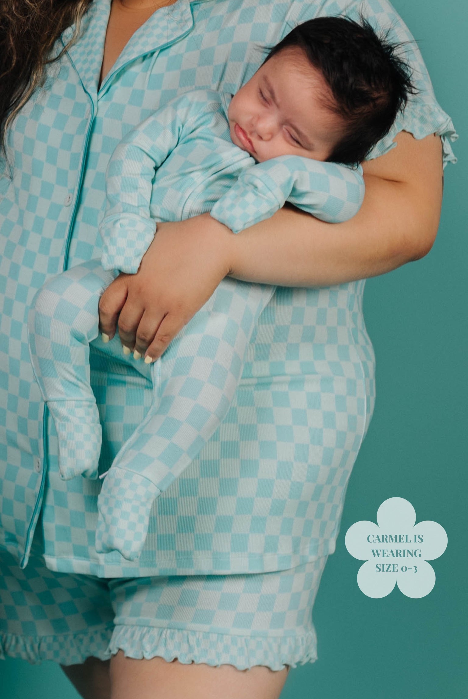 Person wearing a matching teal checkered outfit with a baby