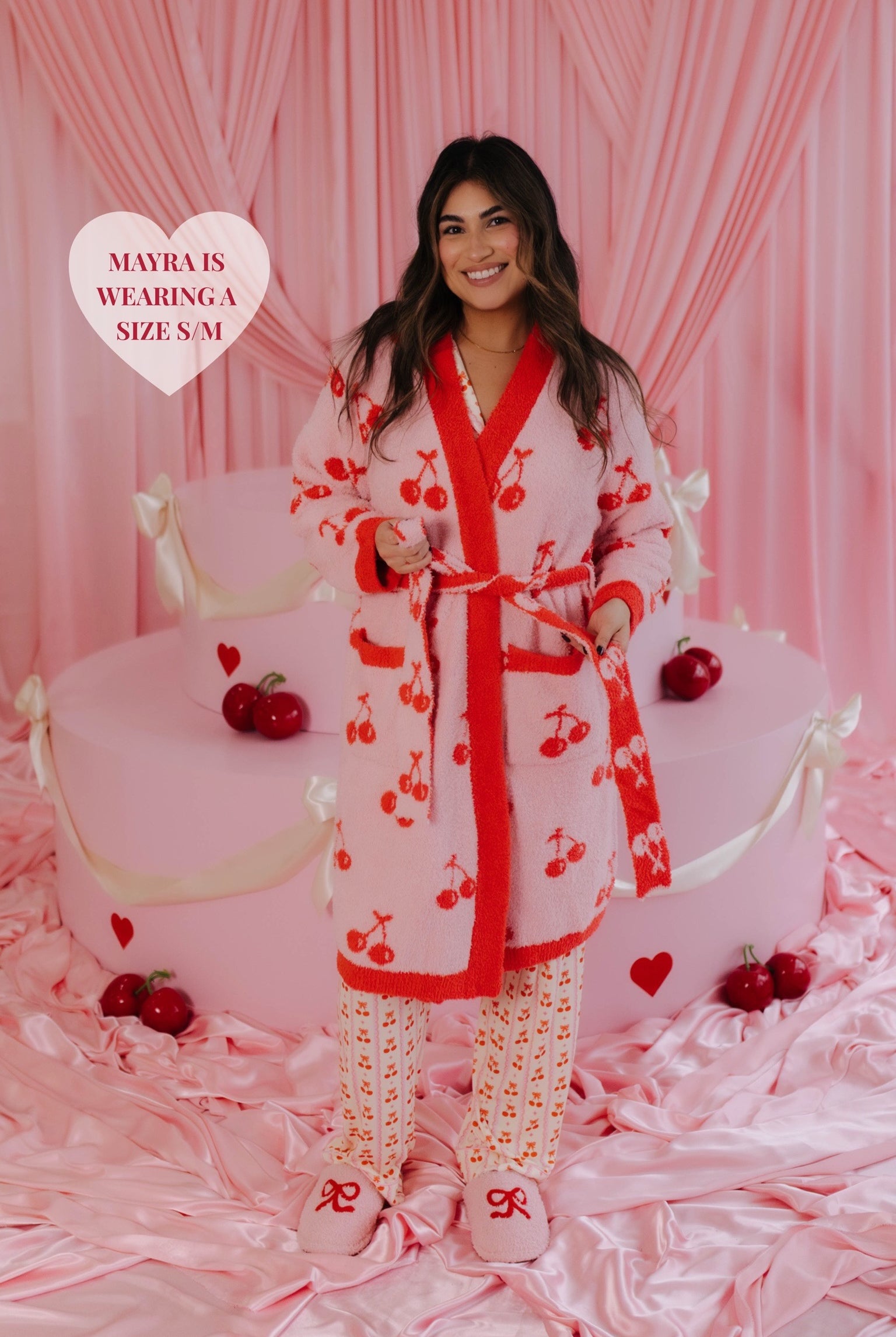 Mayra showing the tie of the robe by holding it in front of the cake set up