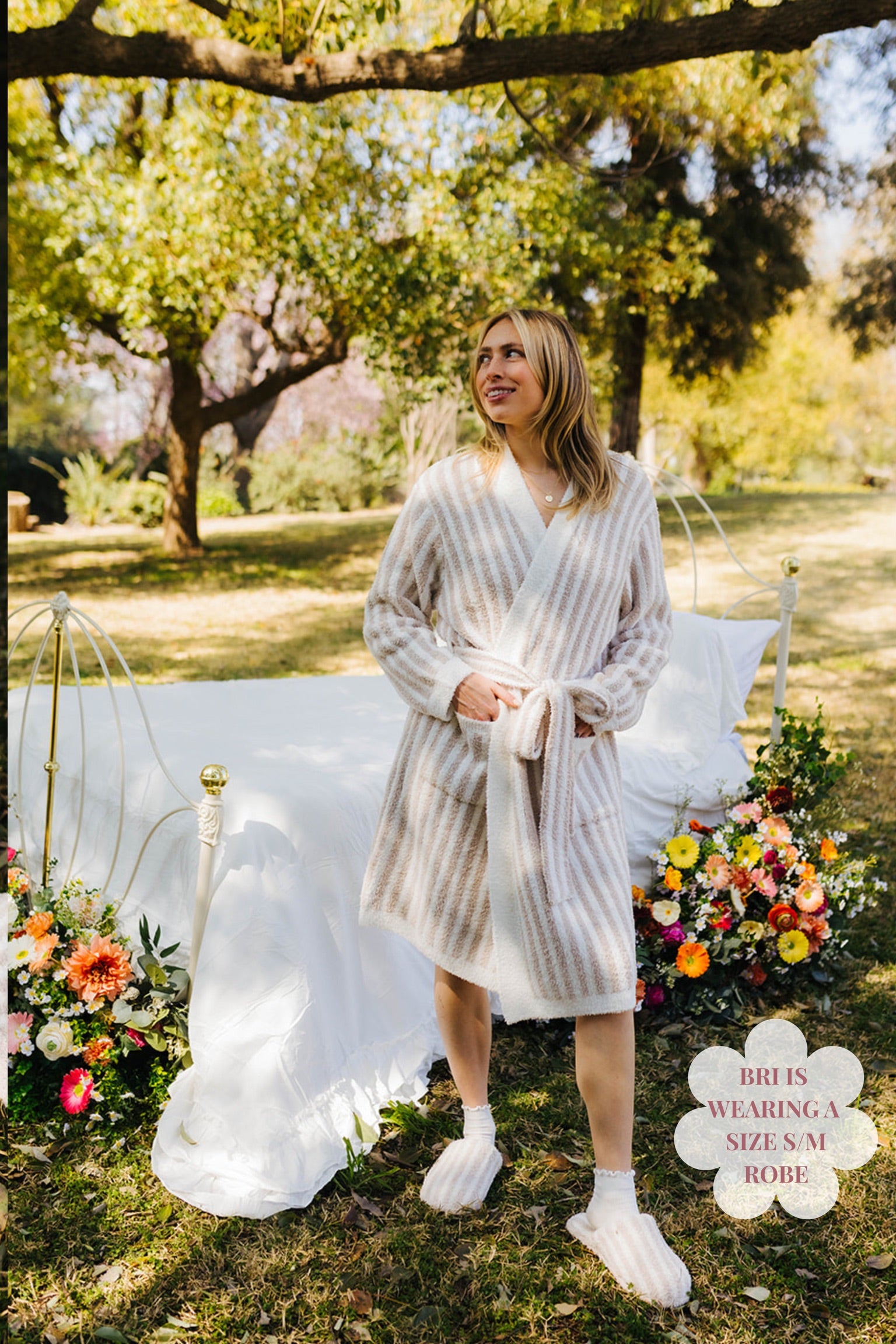 Woman in a striped robe standing outdoors with floral decorations and a bed in the background
