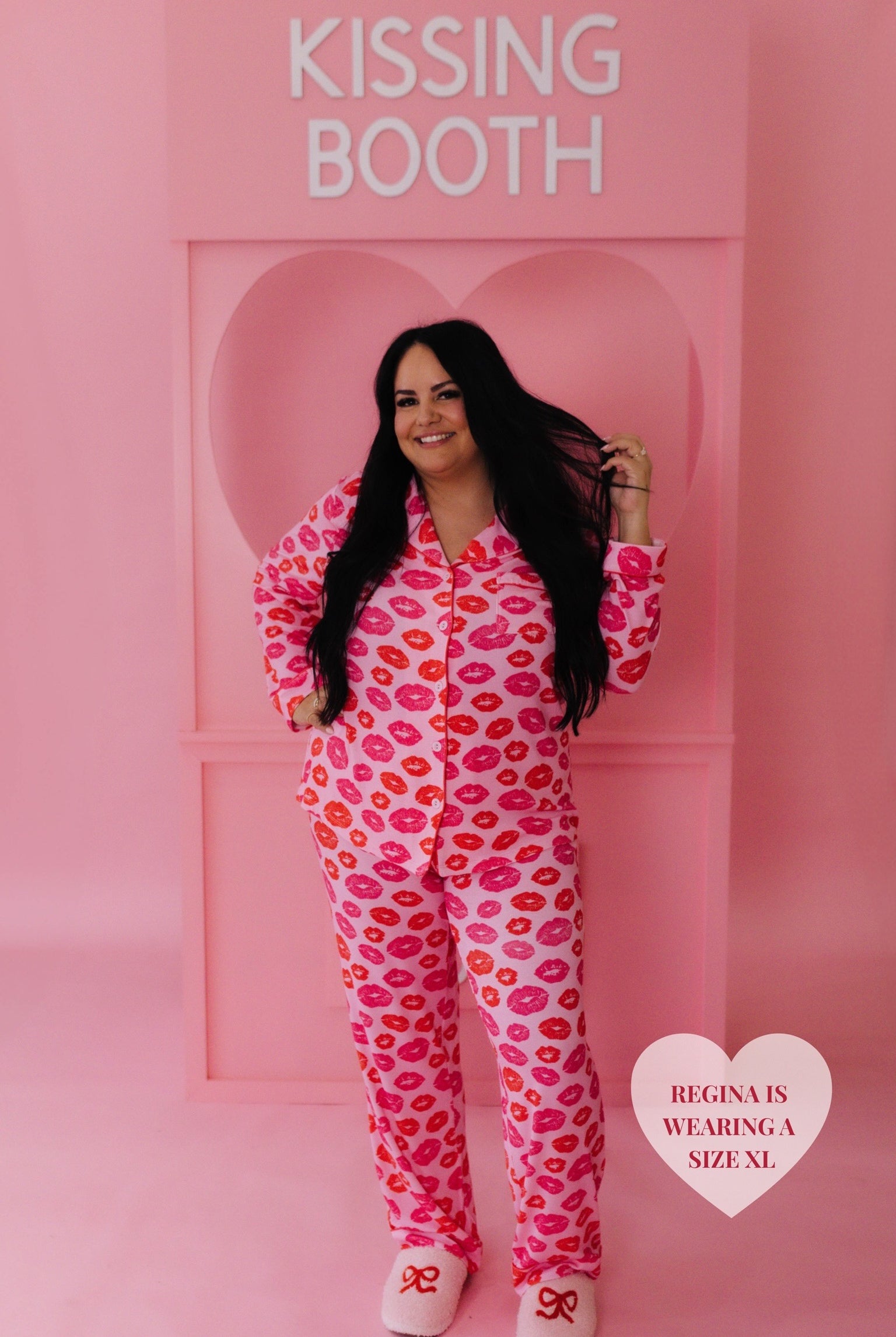 Regina wearing an XL - holding her hair and smiling in front of the kissing both