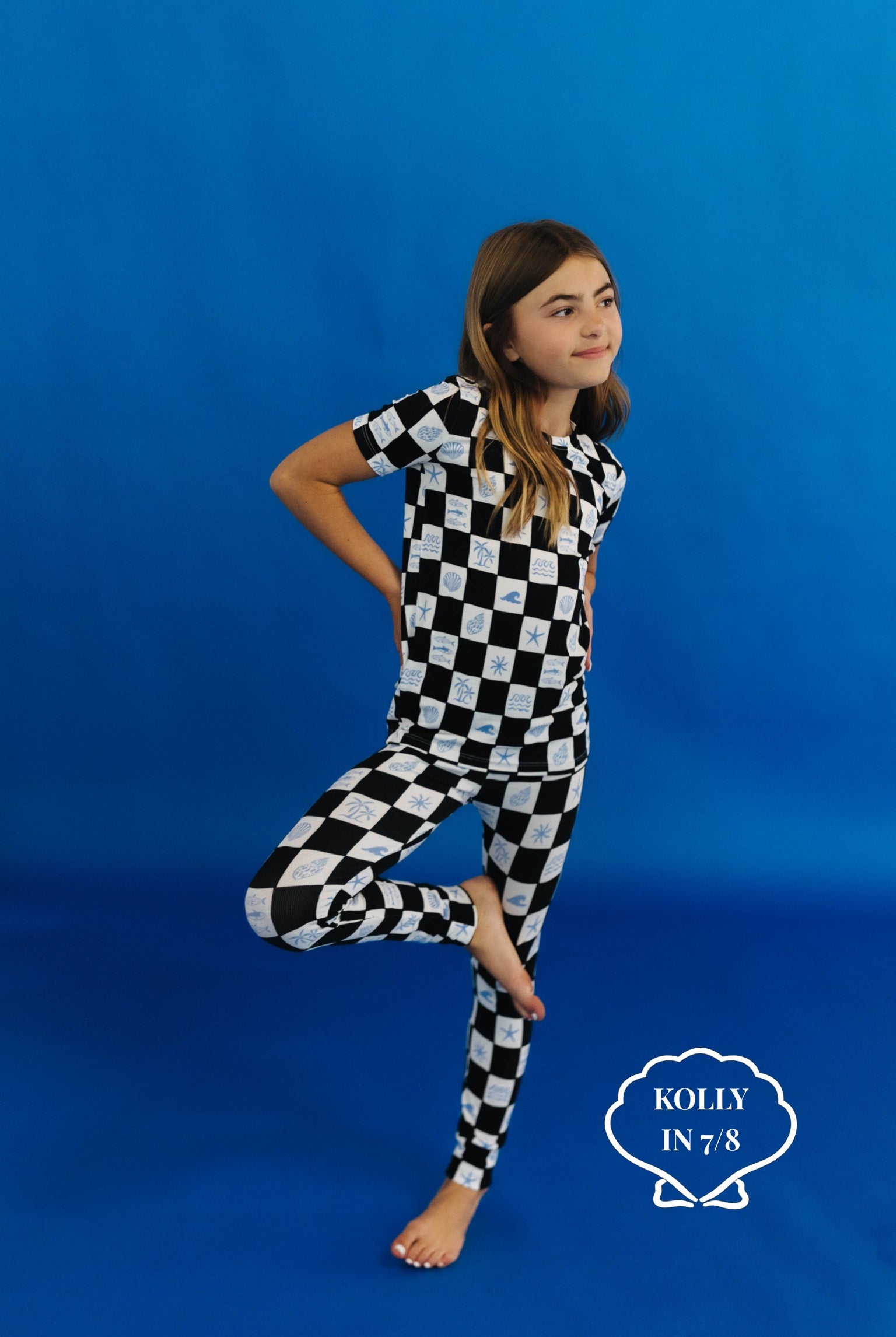 Child wearing a black and white checkered pj set on a blue background size 7/8
