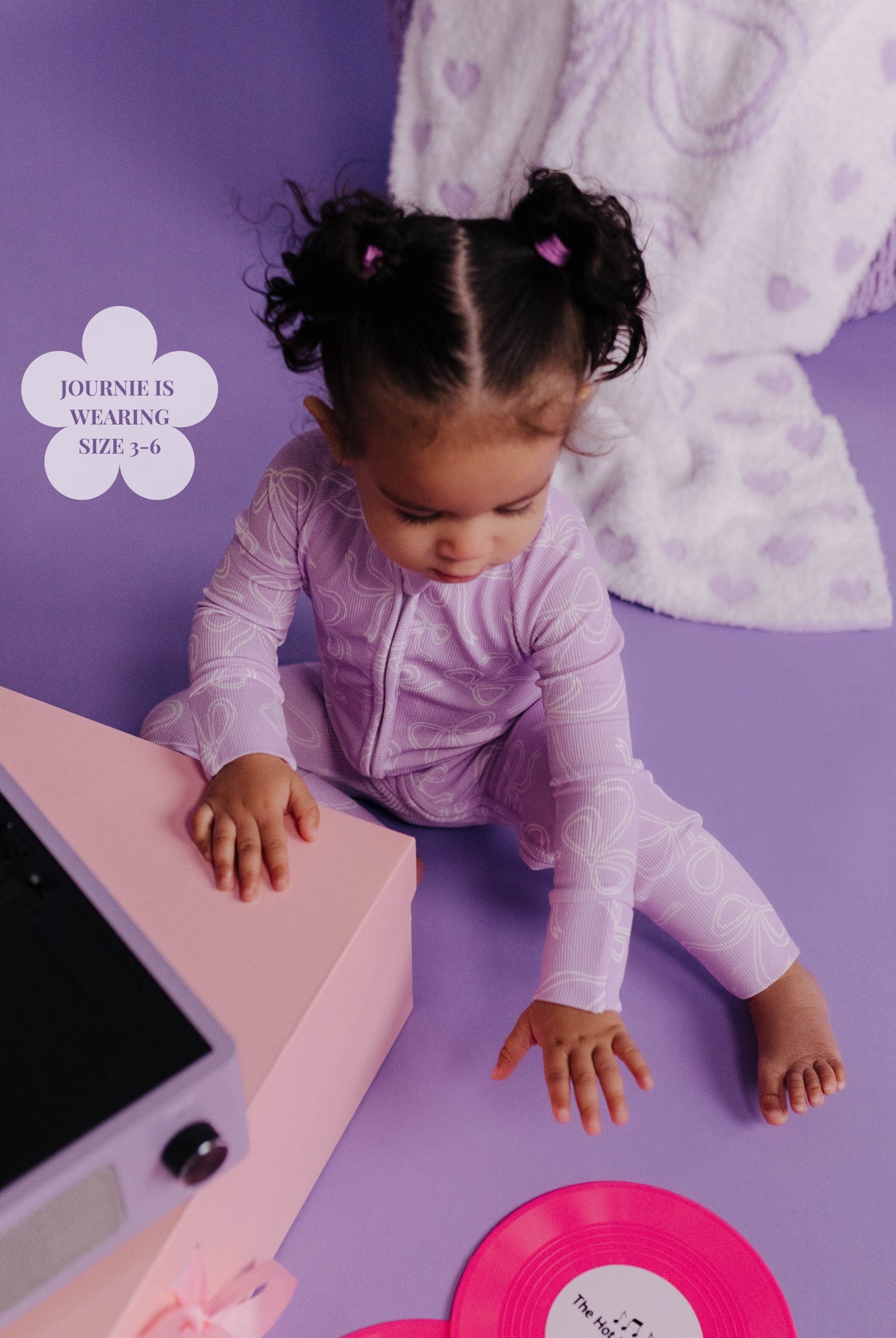 Child playing with a toy on a purple floor with a white blanket