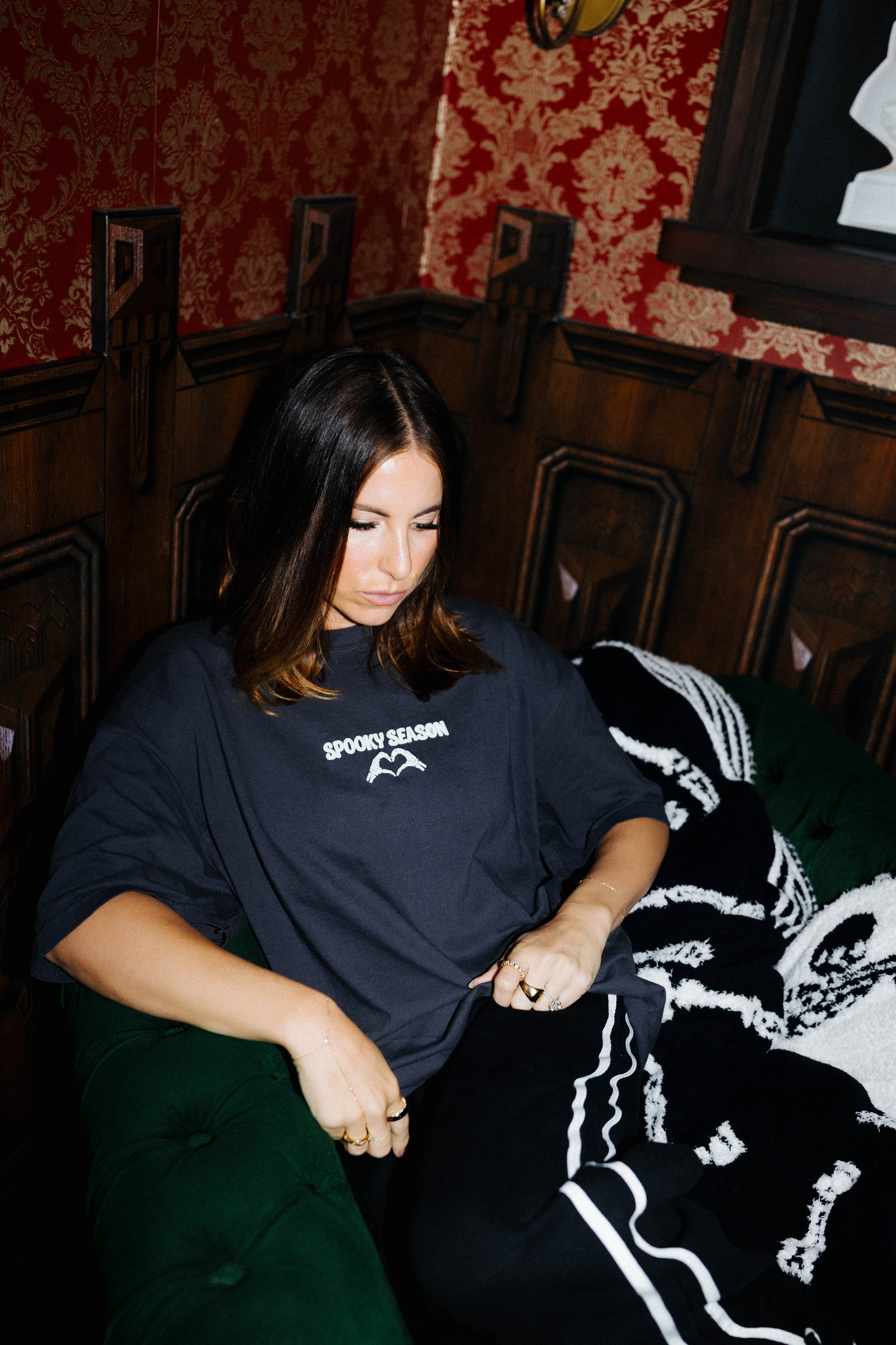 Model wearing a Spooky Season tee while seated on a sofa