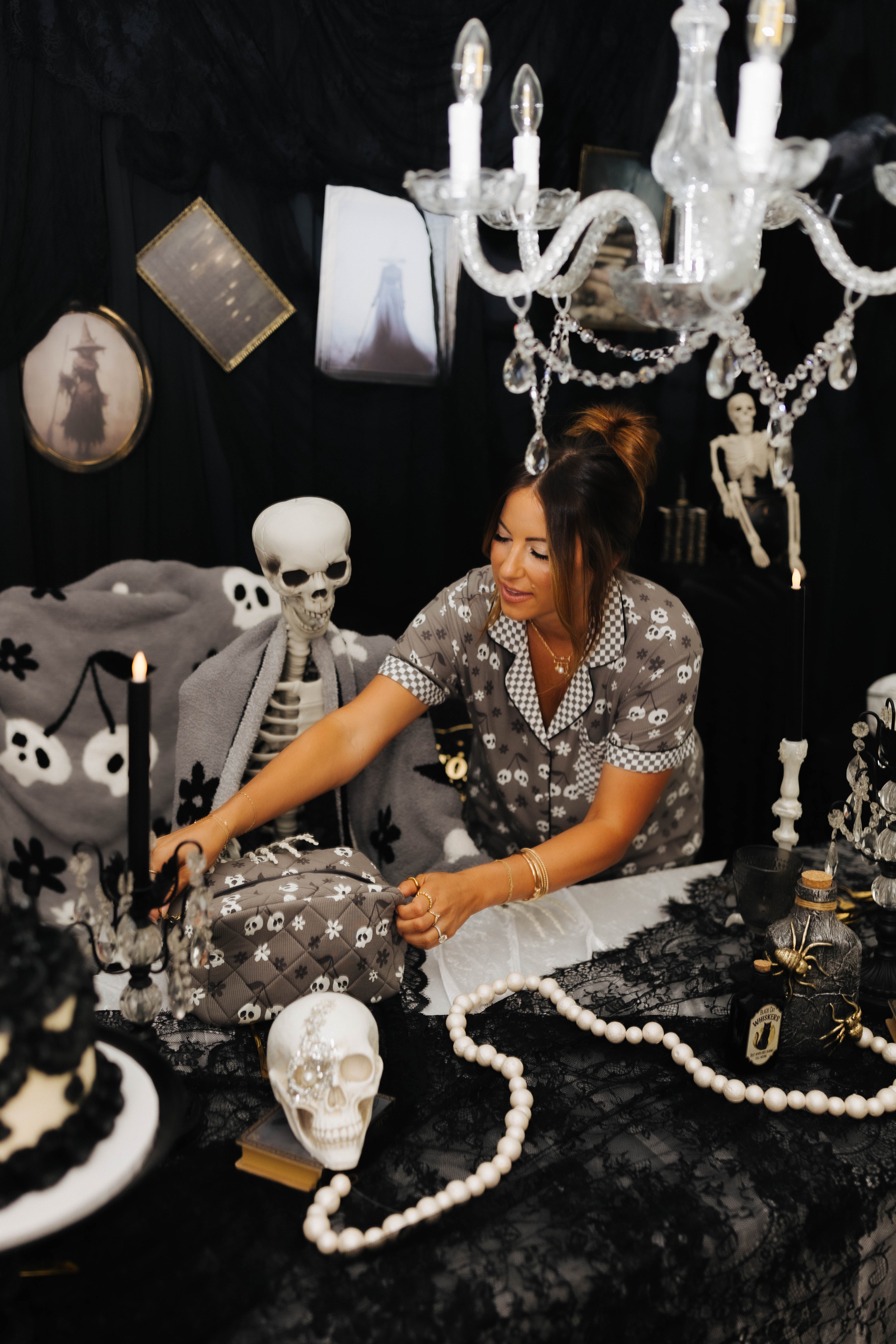 model krista opening skelly cosmetic bag on the table with spooky decorations in the background