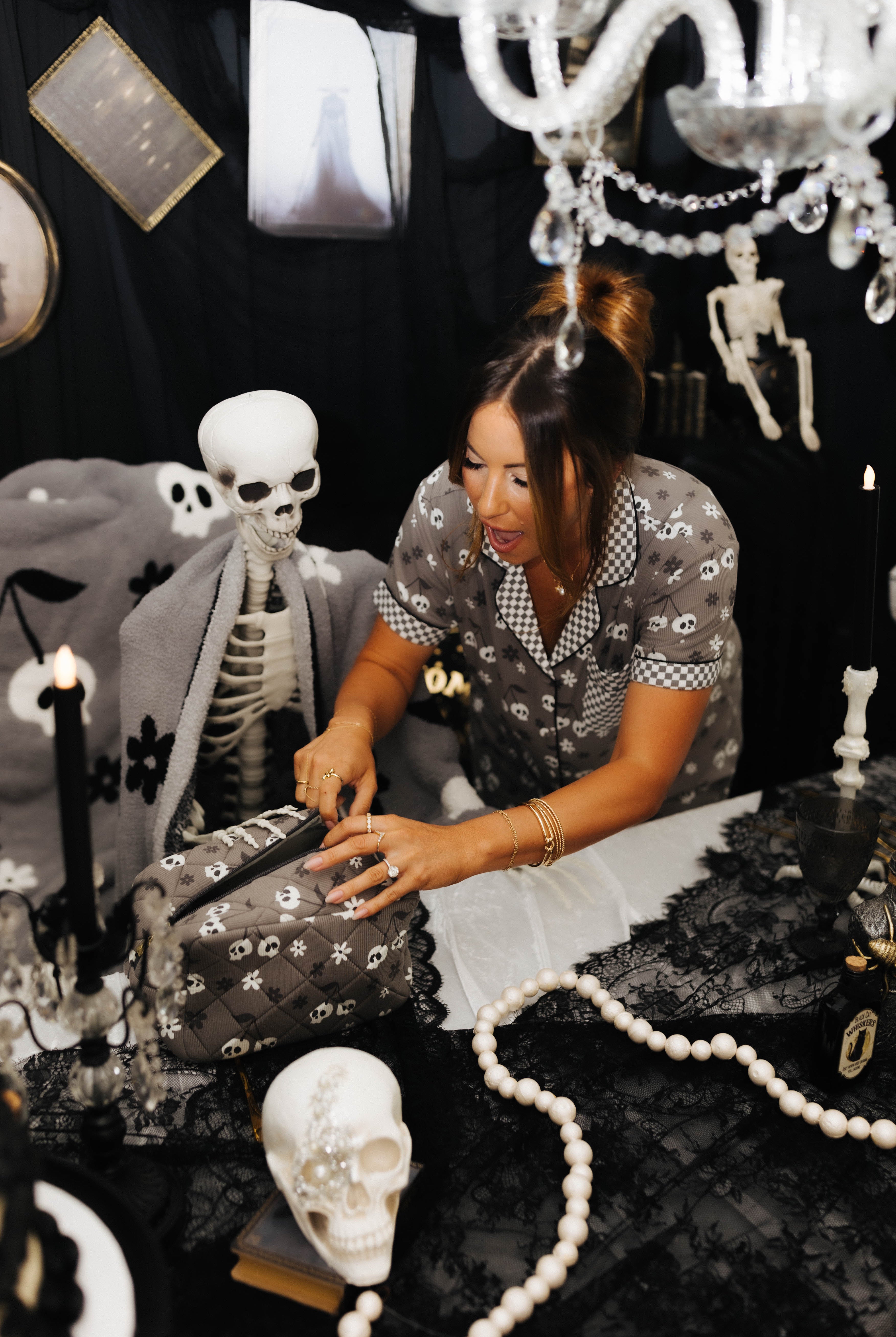 model krista opening the skelly cosmetic bag with spooky decorations in the background