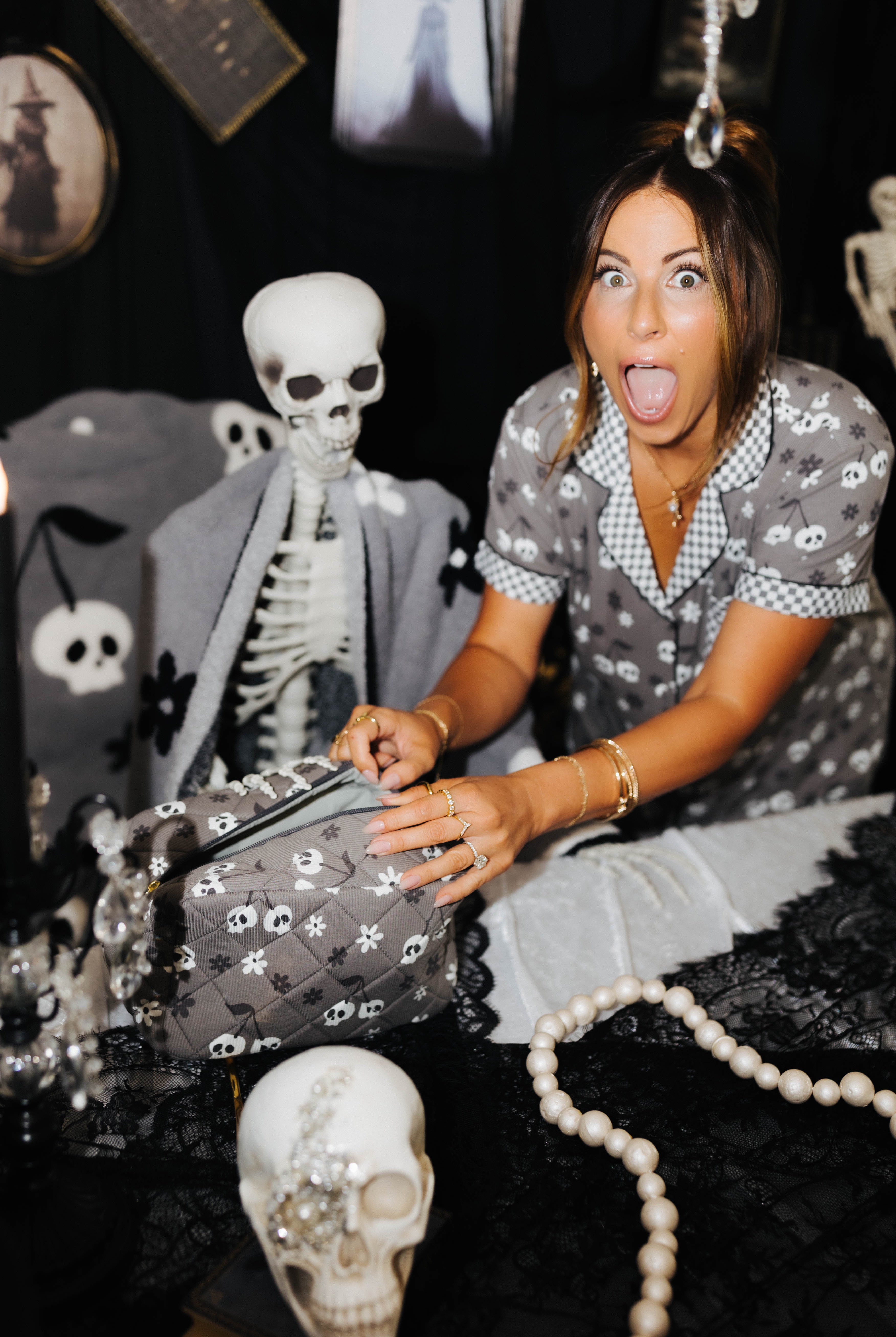model krista with scared face opening skelly cosmetic bag with spooky decorations in the background