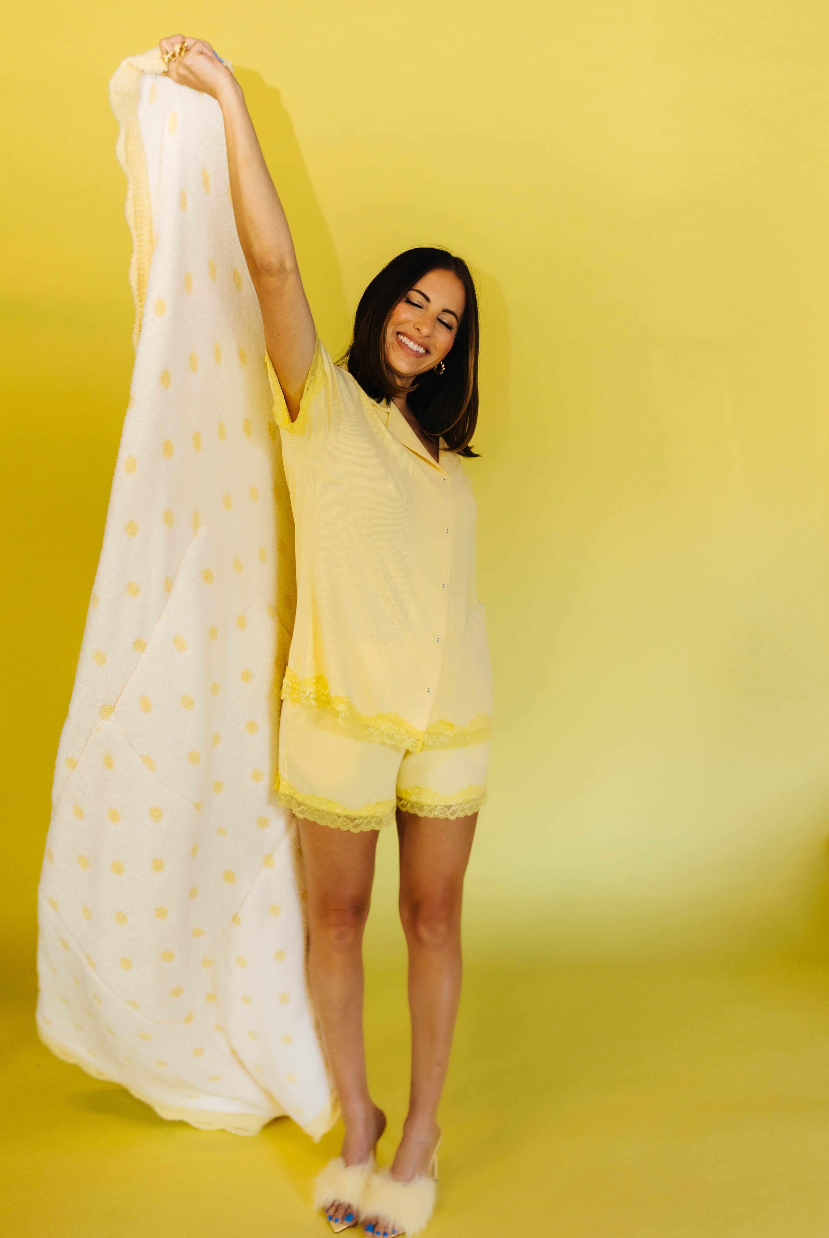 krista holding up the quiillow in the yellow pjs on yellow background
