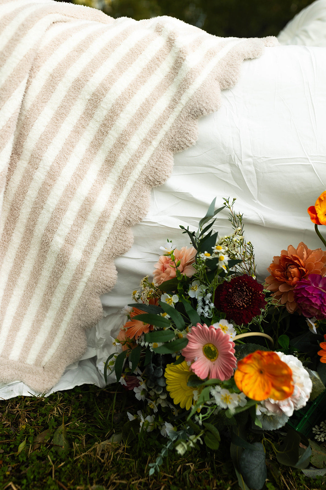 Bouquet of flowers on grass with a blanket in the background