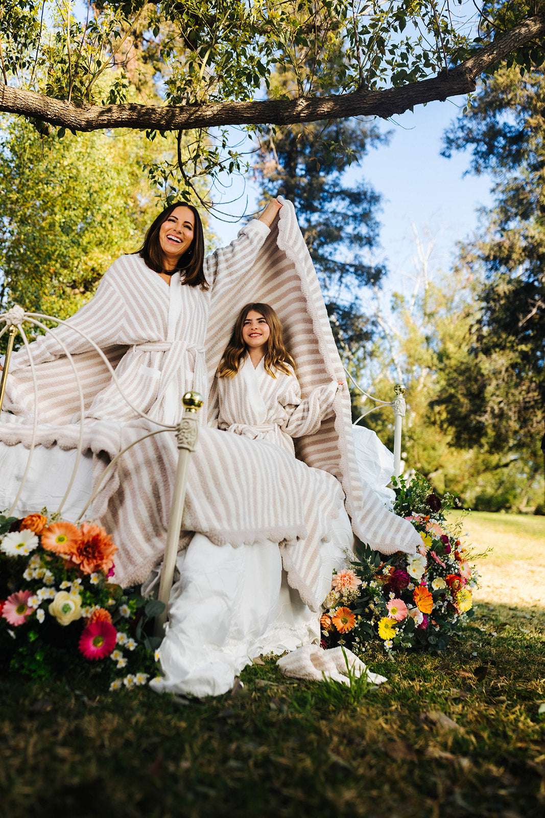 Two women in robes sitting under a tree with flowers around them.