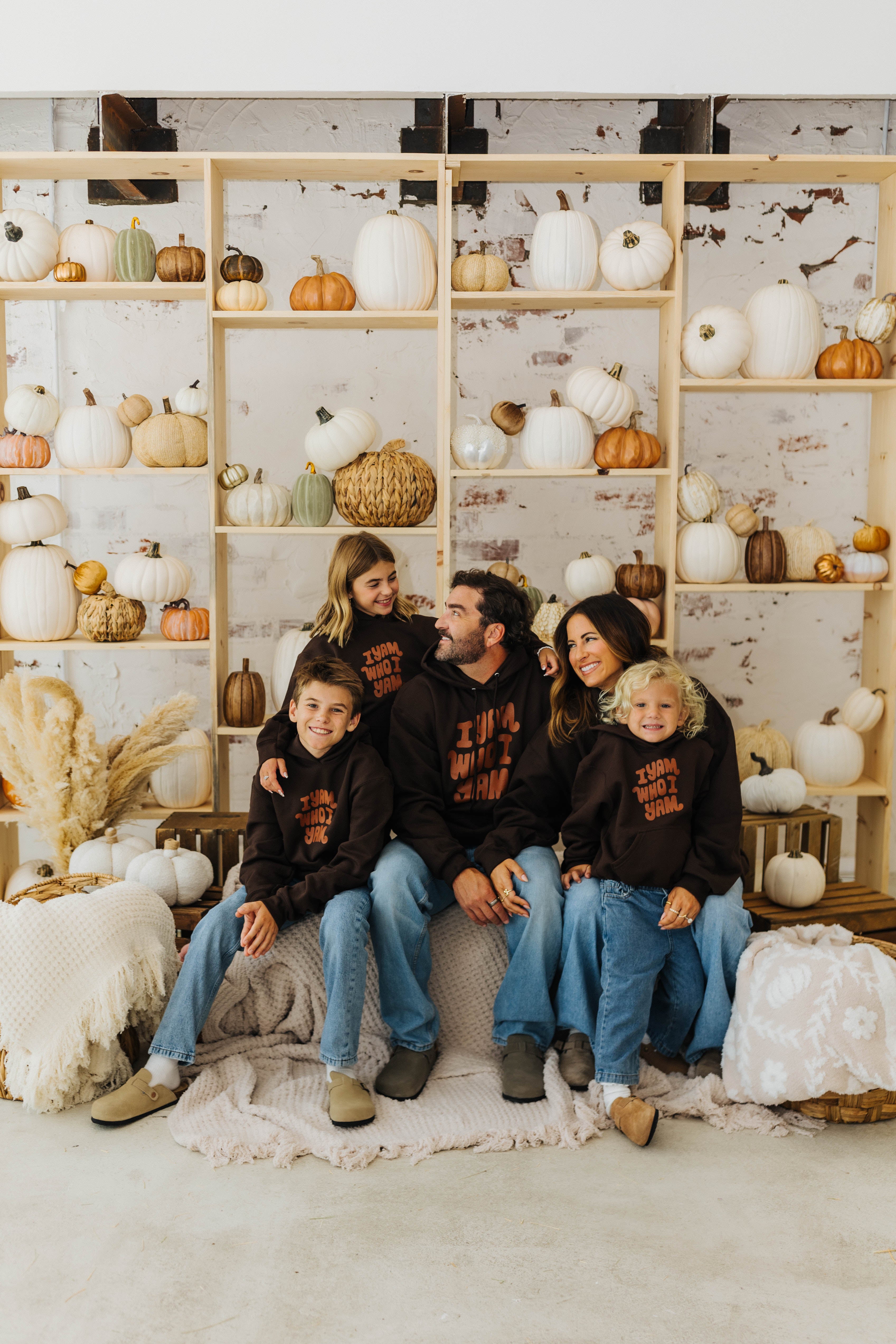 family smiling at each other with blankets sitting neatly in baskets with pumpkin decorations in the background