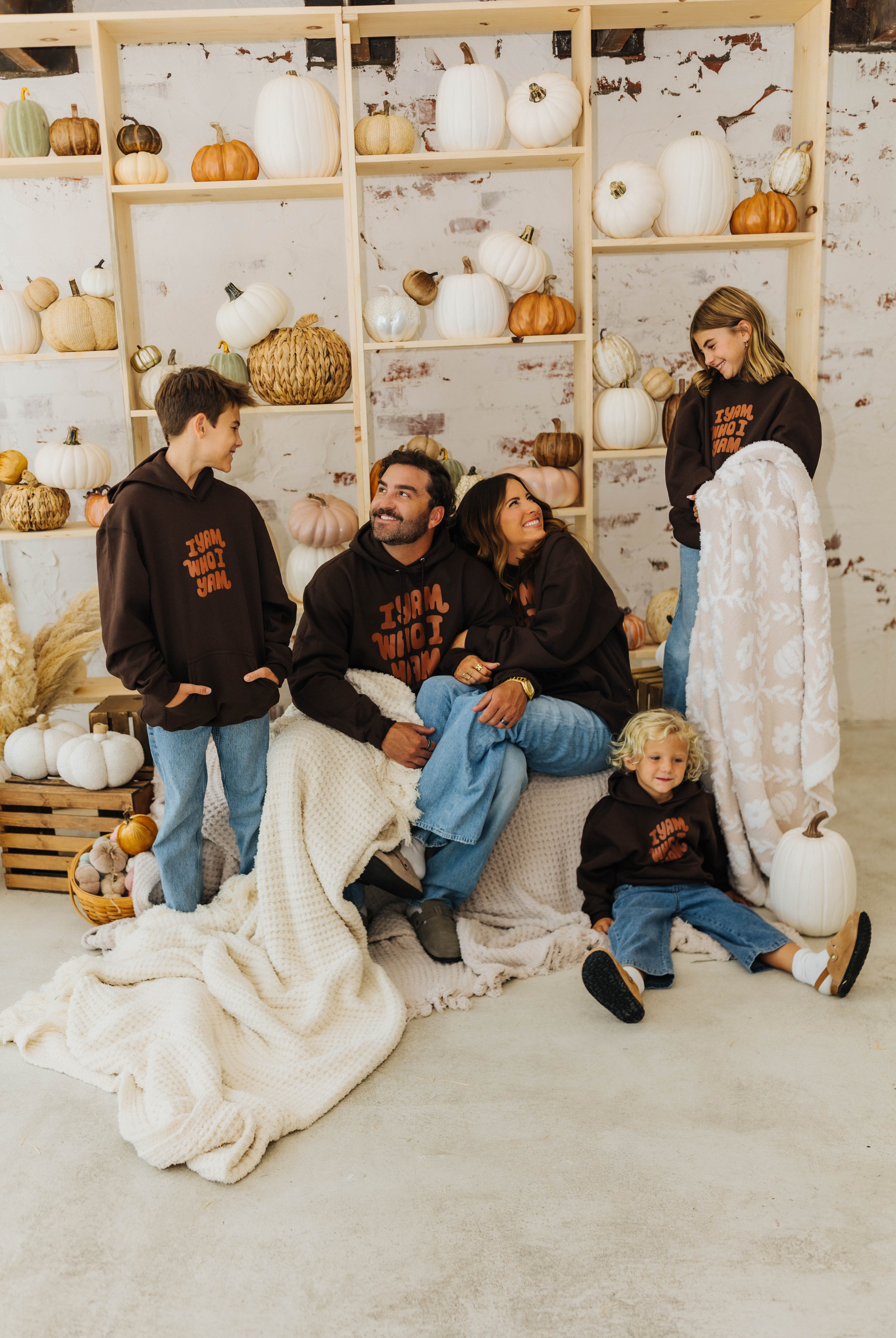 family smiling at each other with waffle blankets wrapped around them and holding pumpkin blanket