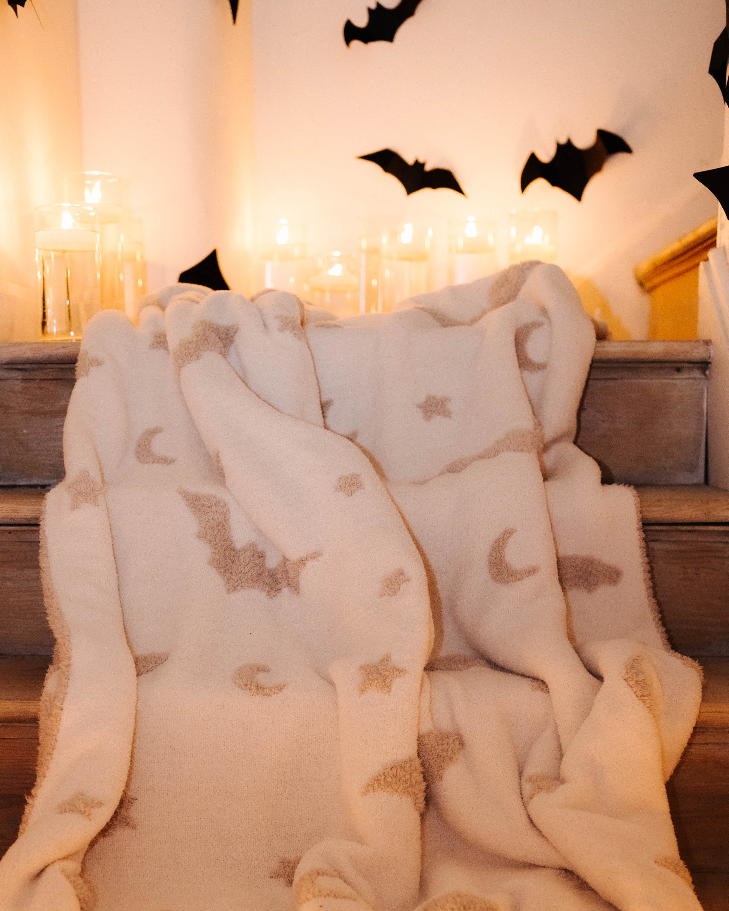bat blanket laying on staircase with candles and bat decorations in the background