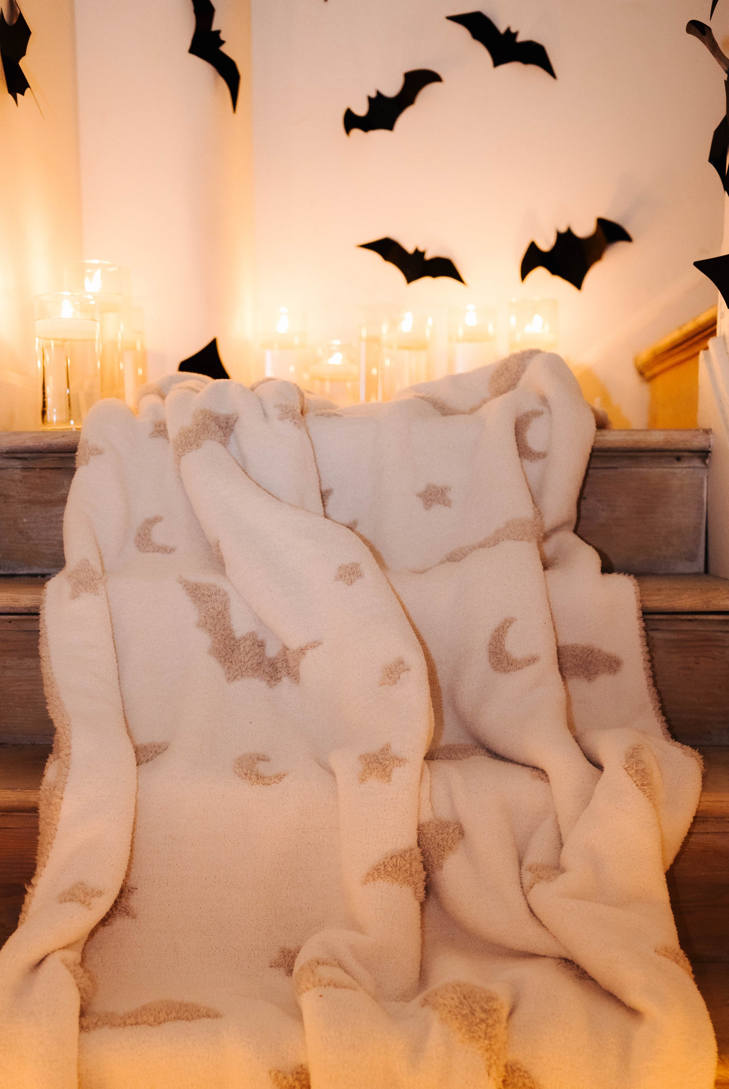 bat blanket laying on staircase with candles and bat decorations in the background