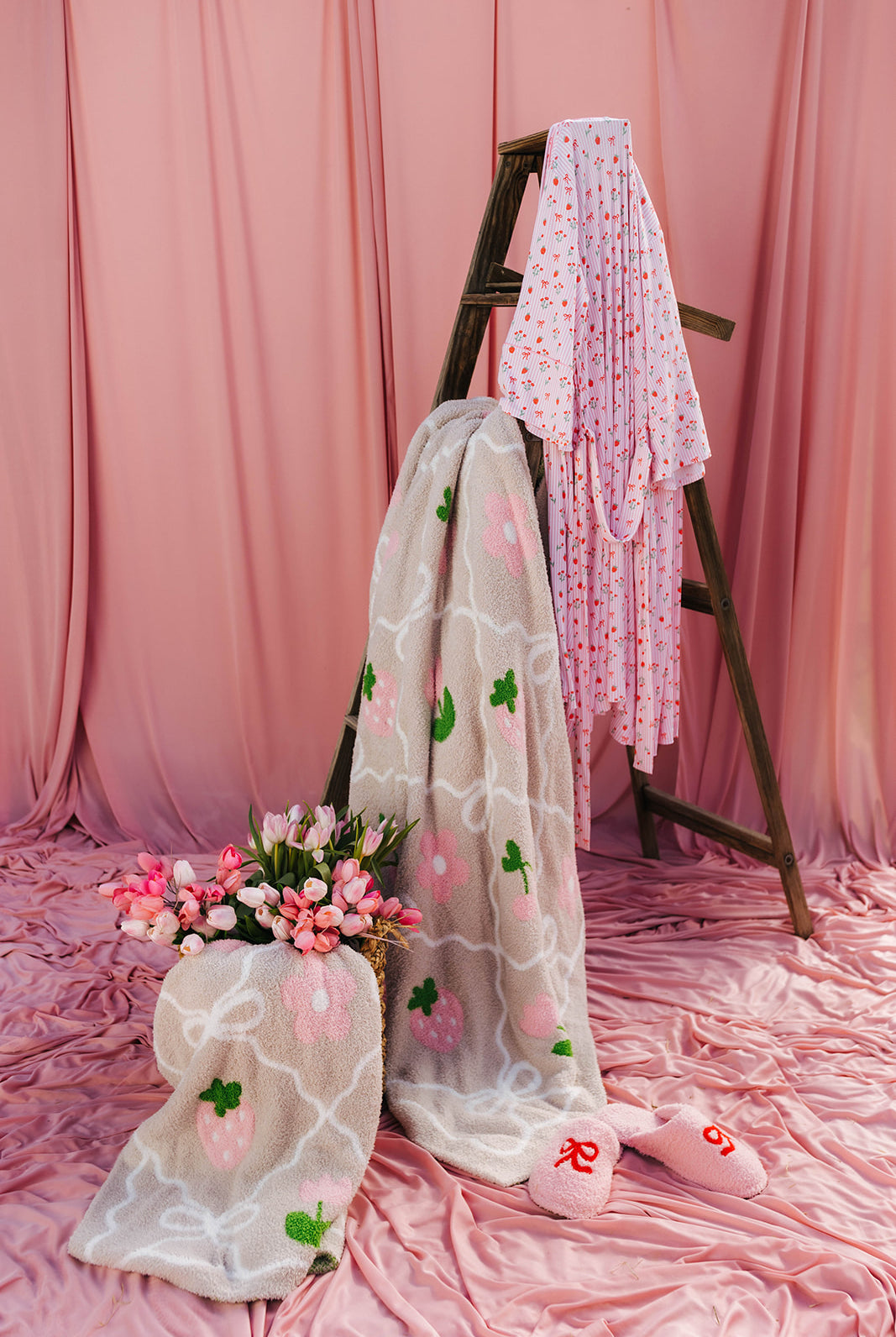 blankets and a ladder with pink floral decorations against a pink curtain backdrop