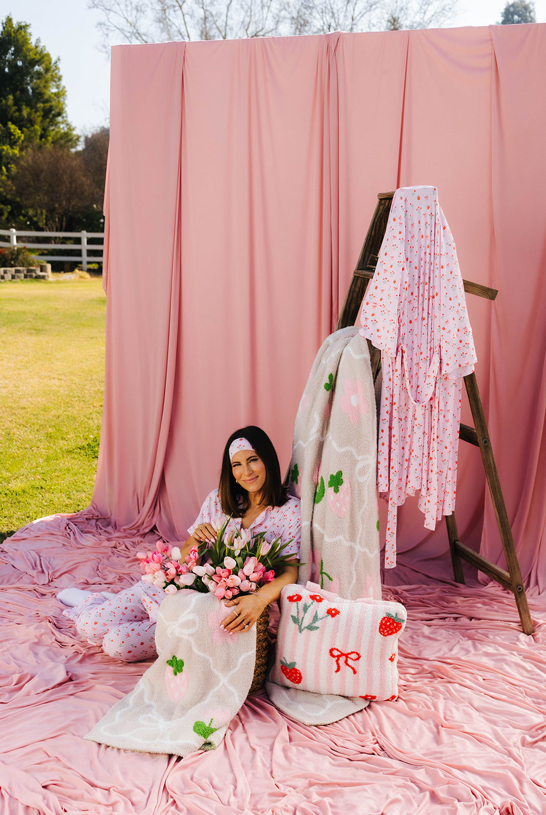 Krista sitting surrounded by the strawberry blankets with the robe hanging