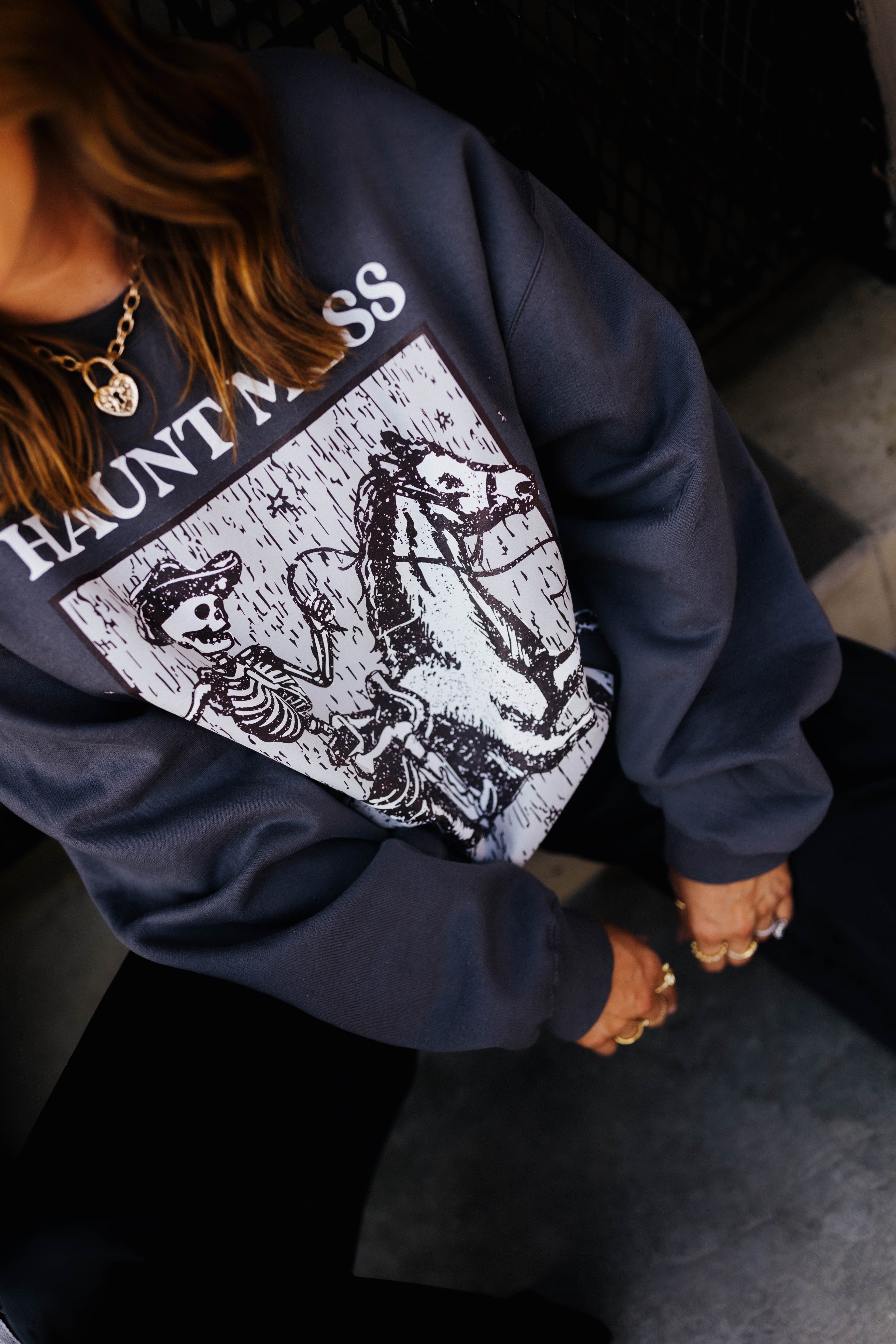 model krista sitting on the curb showing close up of haunt mess express sweatshirt