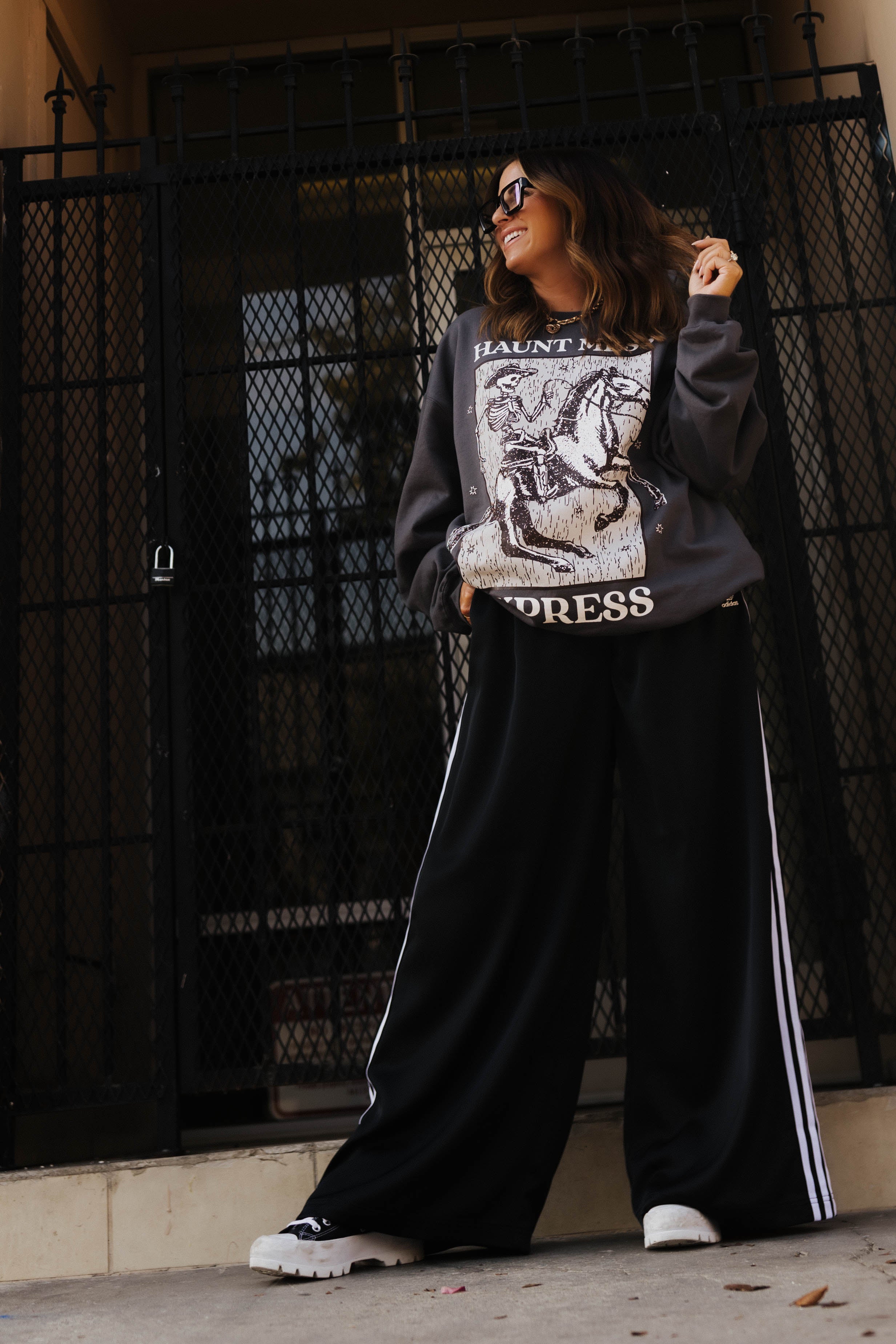 model krista smiling looking away wearing haunt mess express sweatshirt outside on the sidewalk