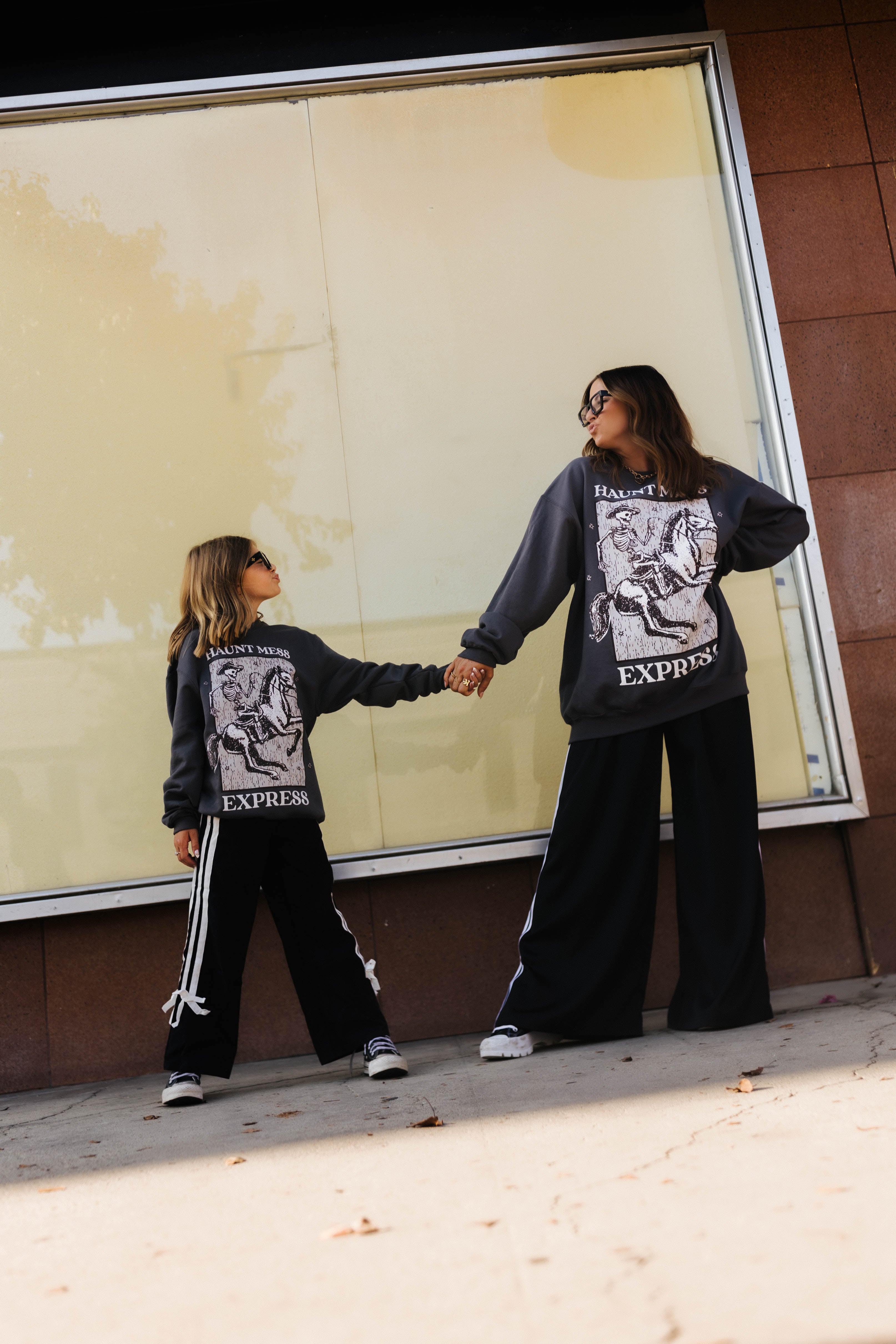 models krista and kolly holding hands doing kissing faces at each other wearing haunt mess express sweatshirts