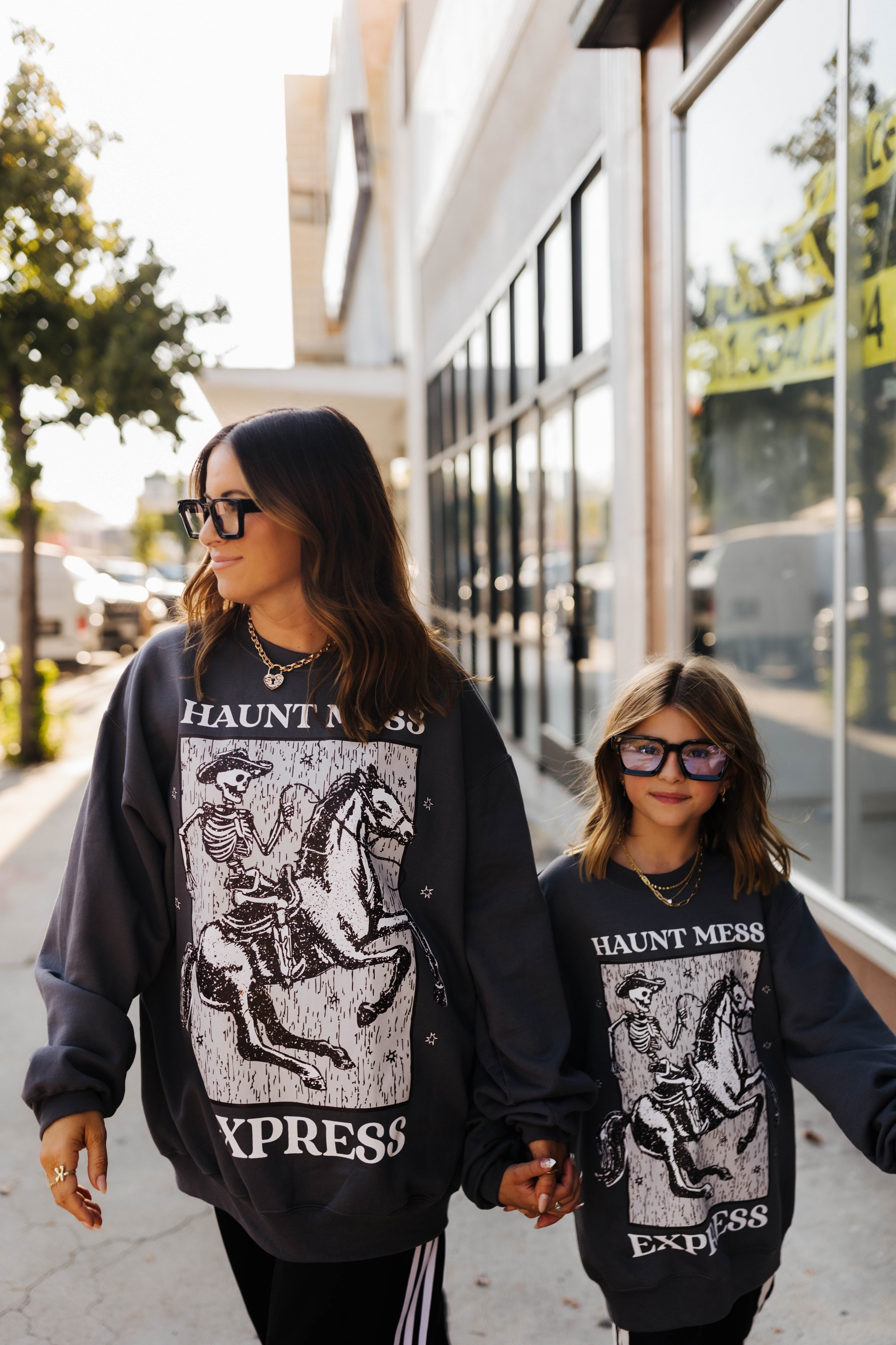 models wearing haunt mess express sweatshirts outside in the street
