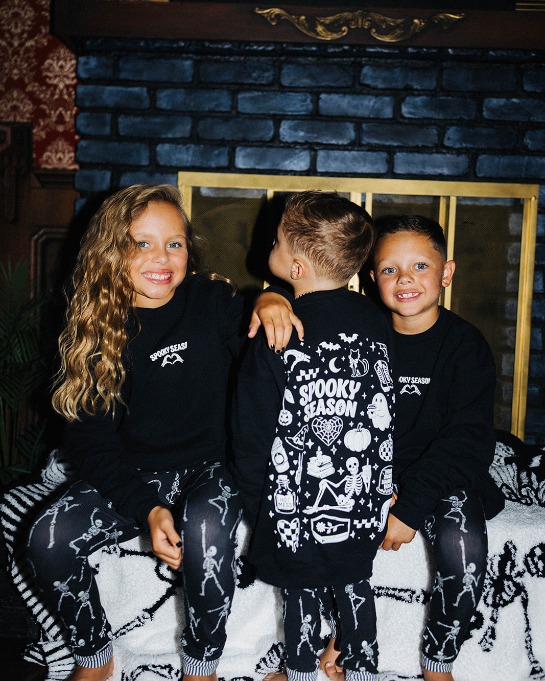 3 kids sitting on a fireplace in matching pjs and sweatshirts