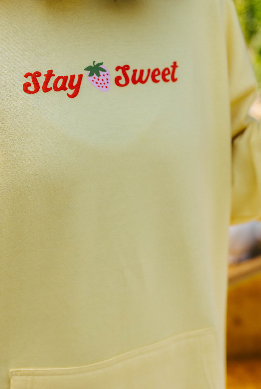 Light yellow hoodie with 'Stay Sweet' text and strawberry graphic.