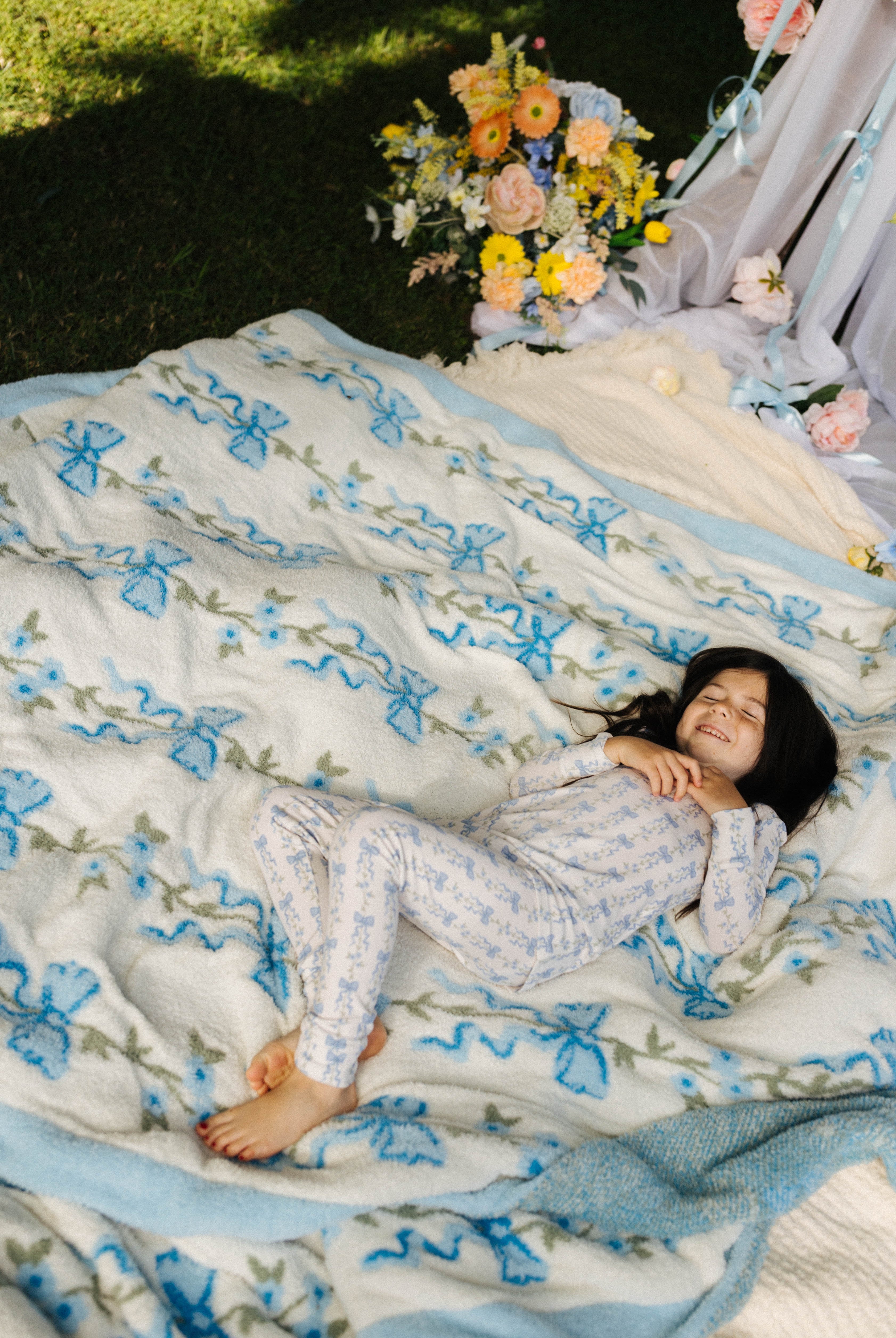 Child lying on the blue blow floral blanket